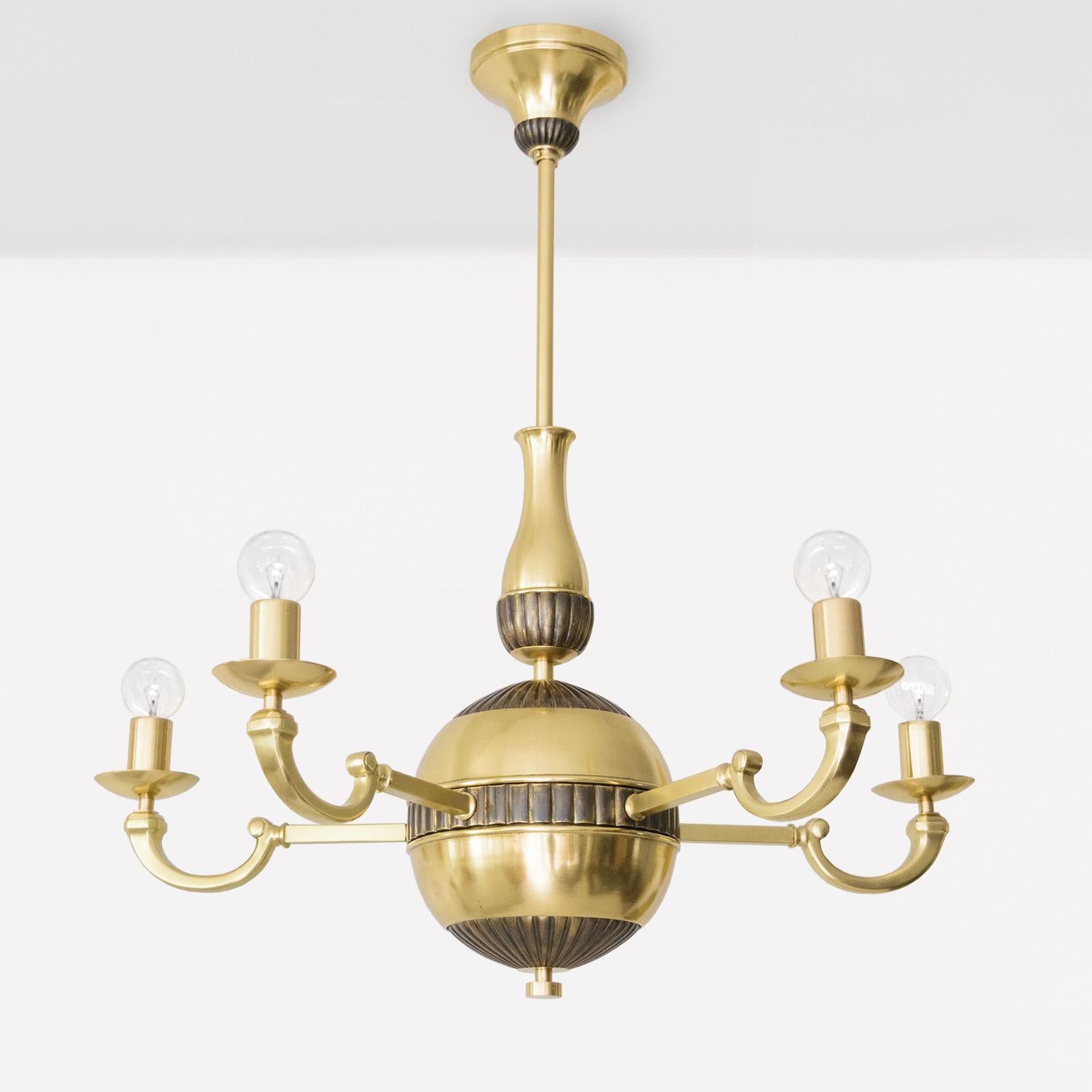 Un lampadario svedese Art Deco a 5 bracci in ottone lucido. Questo pezzo è finemente dettagliato con elementi di superficie in rilievo leggermente patinati. Il lampadario è un ponte tra il modernismo e gli elementi del design classico. Completamente