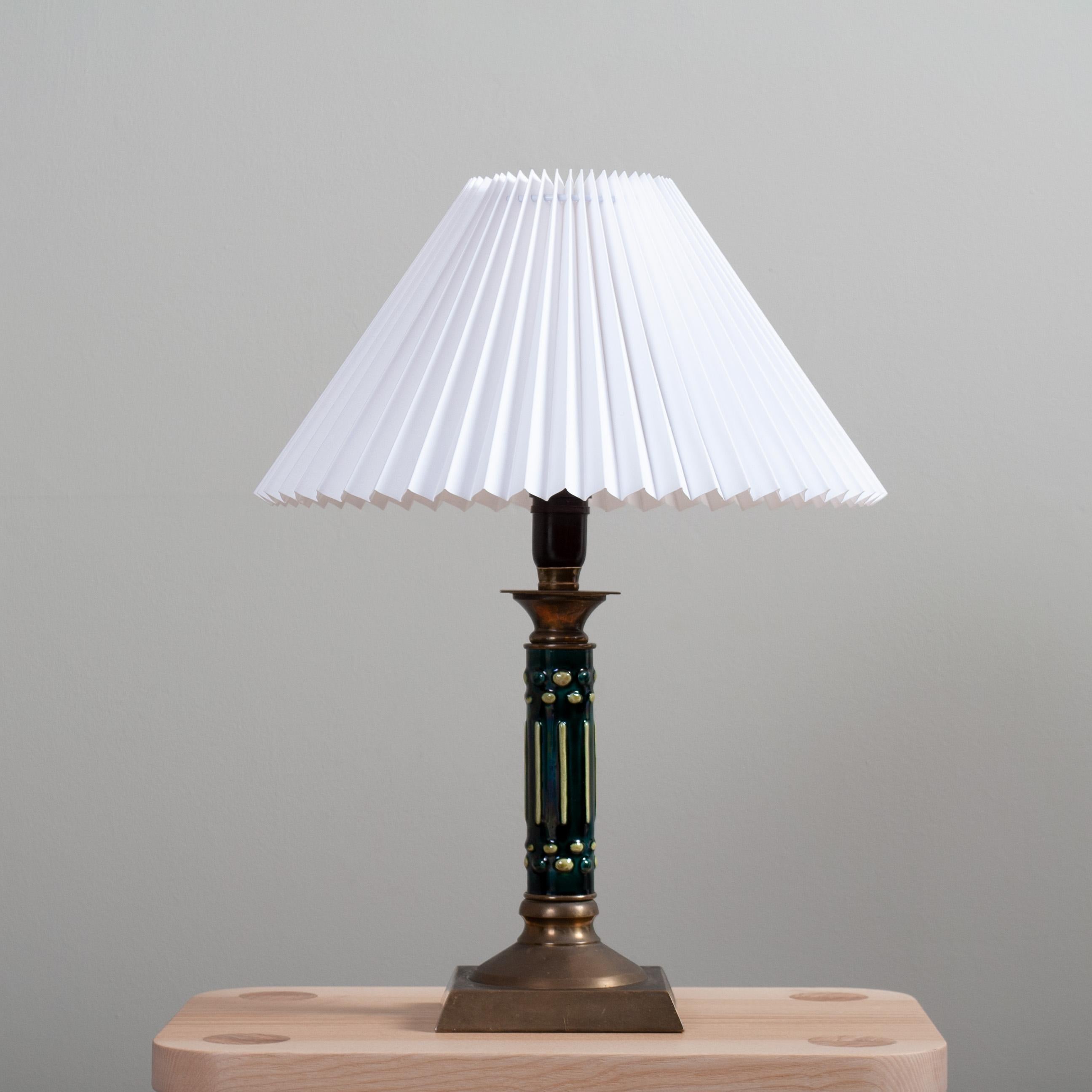 Unusual Swedish ceramic and brass table lamp from the 1930's deco period. 
Lovely design and coloured ceramic upright with solid brass upper and lower parts. The classic Scandinavian pleated clip-on shade is included. Rewired - and can be used in