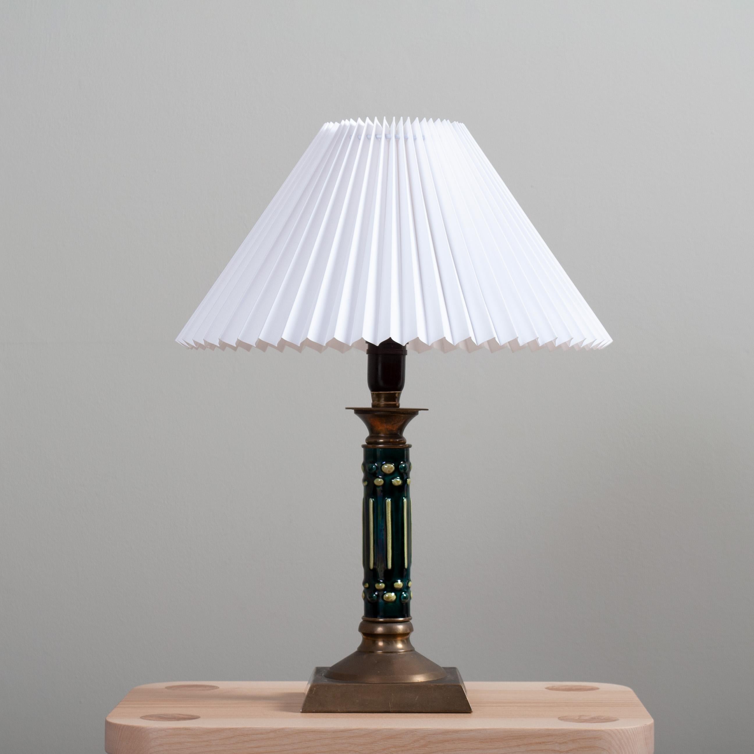 Inhabituelle lampe de table suédoise en céramique et laiton de la période déco des années 1930. 
Joli montant en céramique design et coloré avec des parties supérieures et inférieures en laiton massif. L'abat-jour plissé scandinave classique est