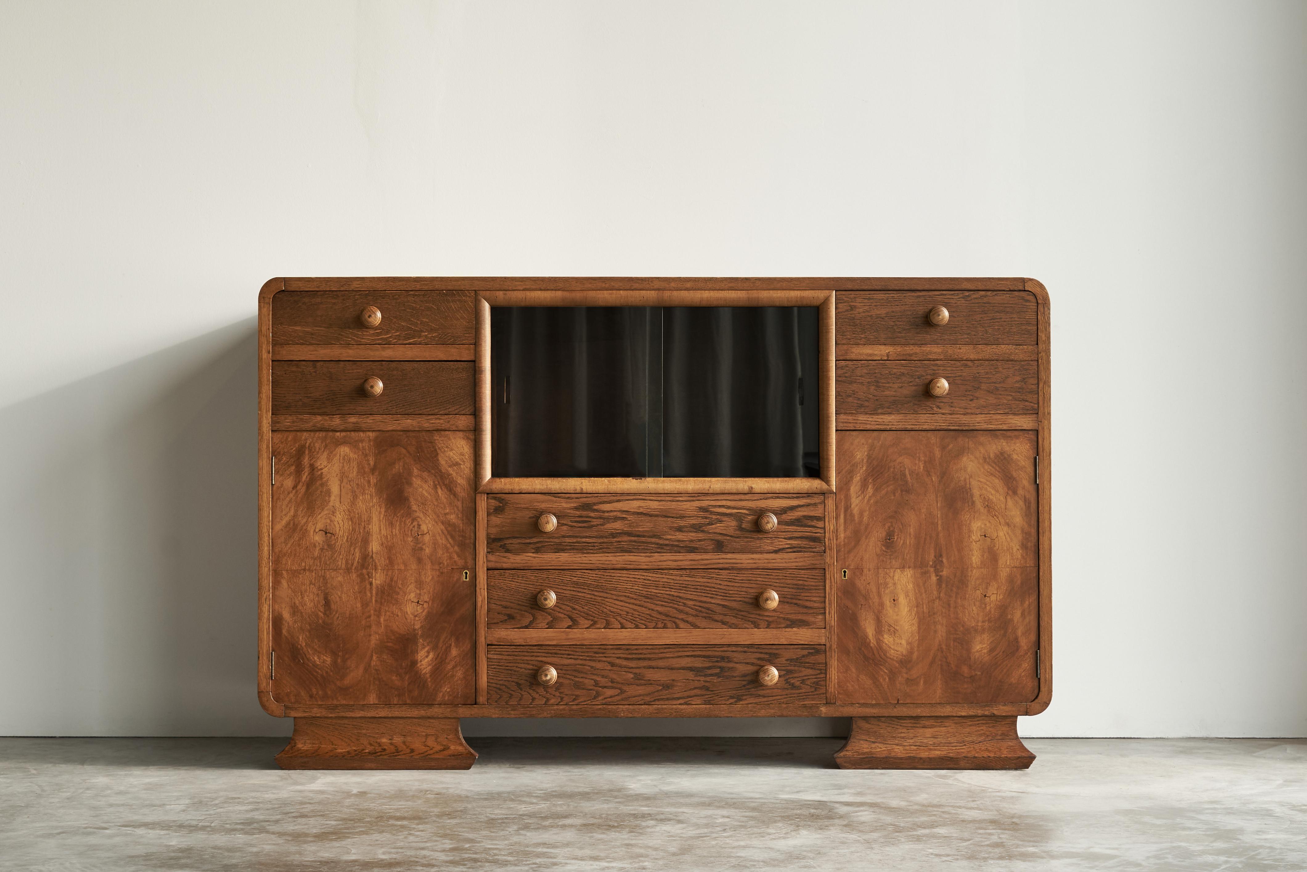 Art Deco Cabinet in Oak, Sweden, 1940s.

Very distinct Art Deco cabinet with glass sliding doors, well executed in oak, oak veneer and oak burl veneer. It origins from Sweden, 1940s.

This cabinet shows a modernistic and symmetrical yet