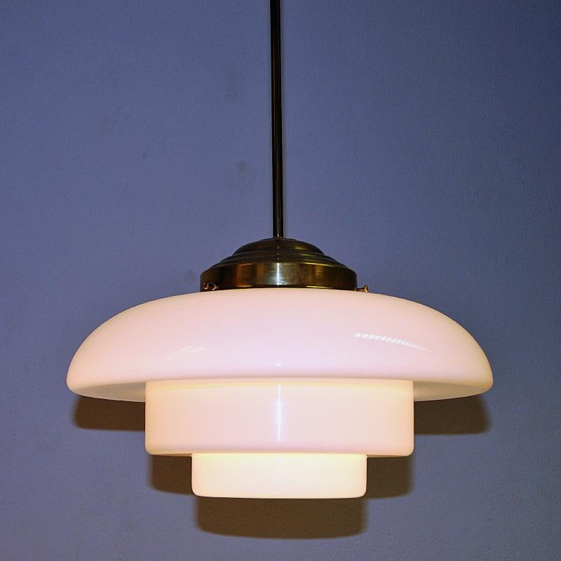 Stunning Swedish Art Deco ceilinglamp from the 1930s - with white opaline glass shade sectioned in three different size levels. The lamp is held up by a solid brass cup and pole all the way up to the ceiling. Gives a beautiful light and atmosphere
