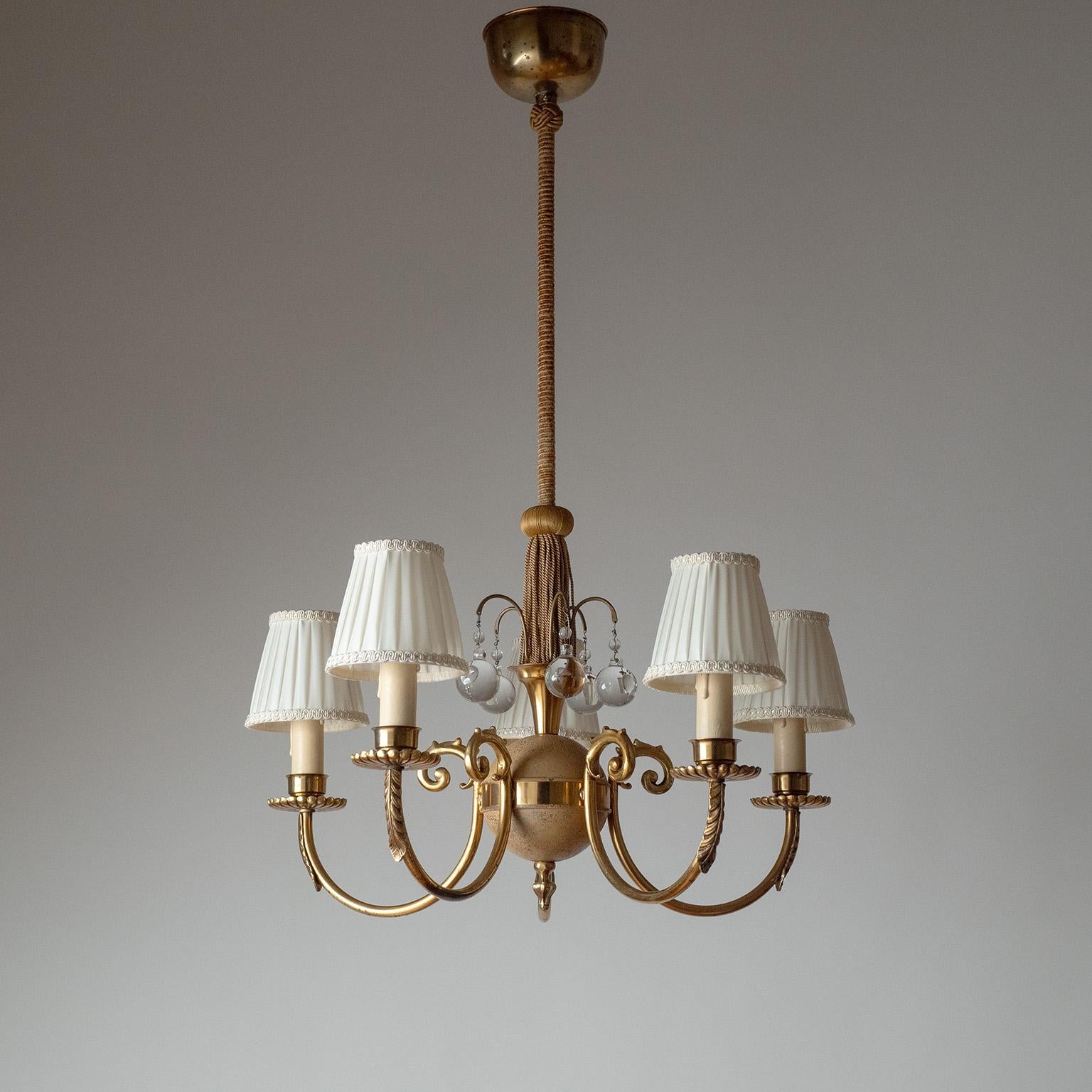 Five-arm Swedish Grace brass chandelier from the 1930s. Sand-colored painted globe centerpiece with small glass globes and fabric trimmings and richly decorated brass arms. Nice original condition with a fair amount of patina on the original paint
