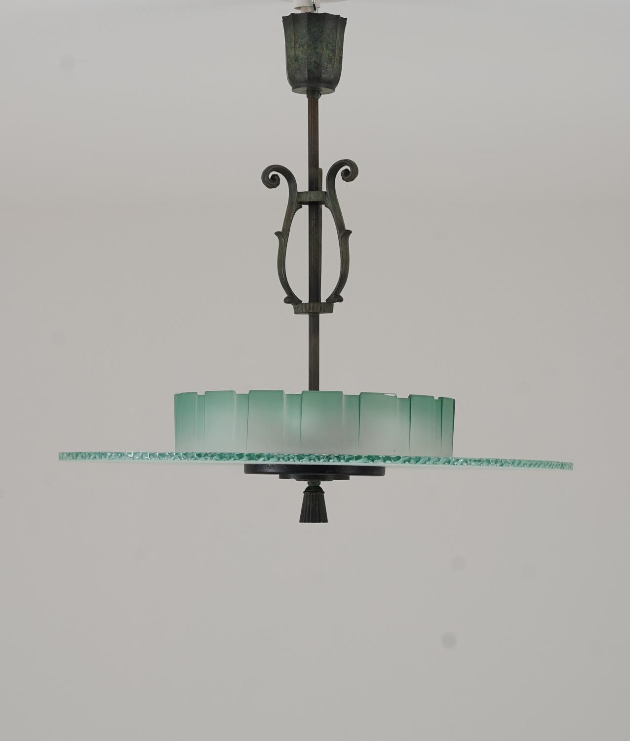Lustre suédois de style Art déco, fabriqué dans les années 1940, présentant une combinaison étonnante de laiton patiné vert et de verre dépoli. Le luminaire se caractérise par son travail sculptural du métal, mettant en valeur d'élégants détails de