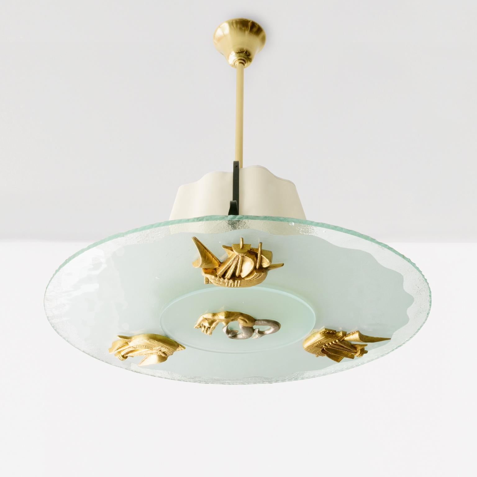 Un affascinante lampadario svedese in stile Art Déco con un paralume in vetro acidato con onde dell'oceano. Tre navi in metallo dorato navigano intorno a una figura di sirena rifinita con foglie d'oro e palladio. Una struttura in ferro battuto