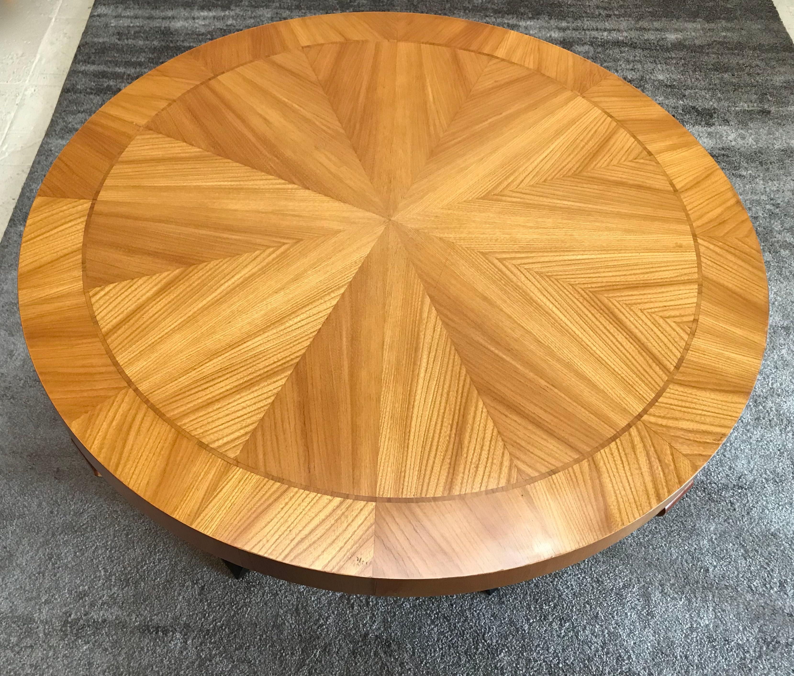 Swedish Art Deco circular centre table, elm book matched top decorated with string inlaid decoration. Flame birch hand-carved scrolled supports onto a platform base resting on ebonized hand-carved feet.