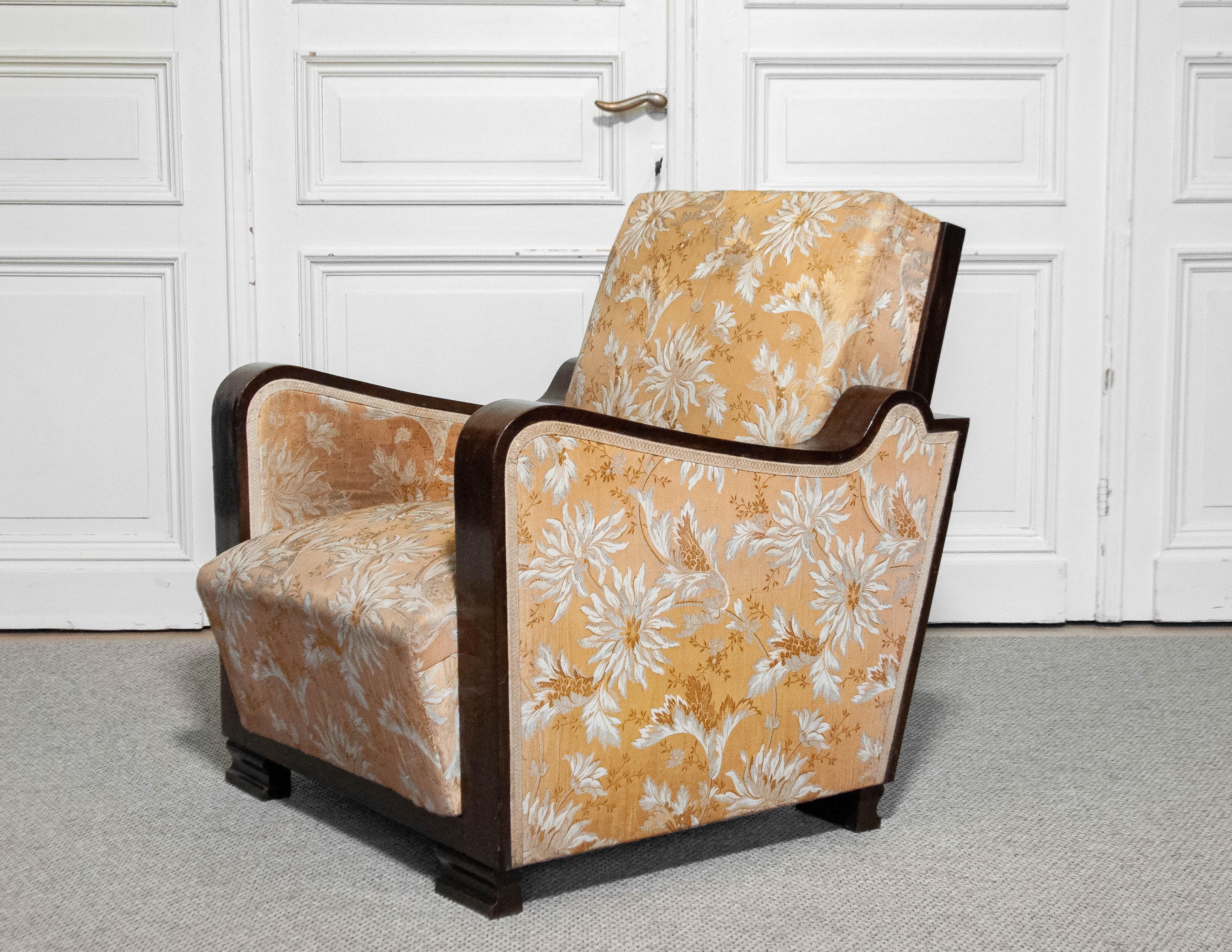 A stunning Swedish Art Deco armchair from the 1920s, featuring its original golden jacquard fabric with an elegant floral pattern. The fabric shows some wear consistent with age and use like little fading and little holes.The chair has a solid beech