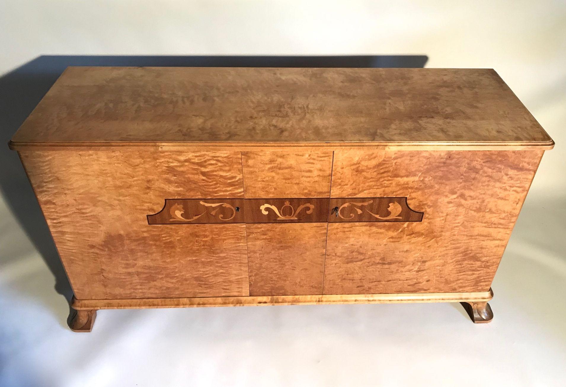 Swedish Art Deco flame birch sideboard with intarsia inlaid decoration of Palisander and exotic timbers. The interior having a fitted drawer and adjustable shelving. A perfectly proportioned piece to fit in any setting or space. Produced by Svenska