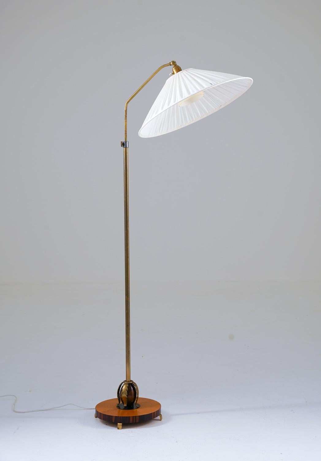 Lovely Art Deco floor lamp manufactured in Sweden, 1940s. 
The lamp consists of a base in zebrawood and elm, with leaf-shaped ornaments in brass. The base supports the brass rod, which is adjustable in height. 
Maximum height is 175cm