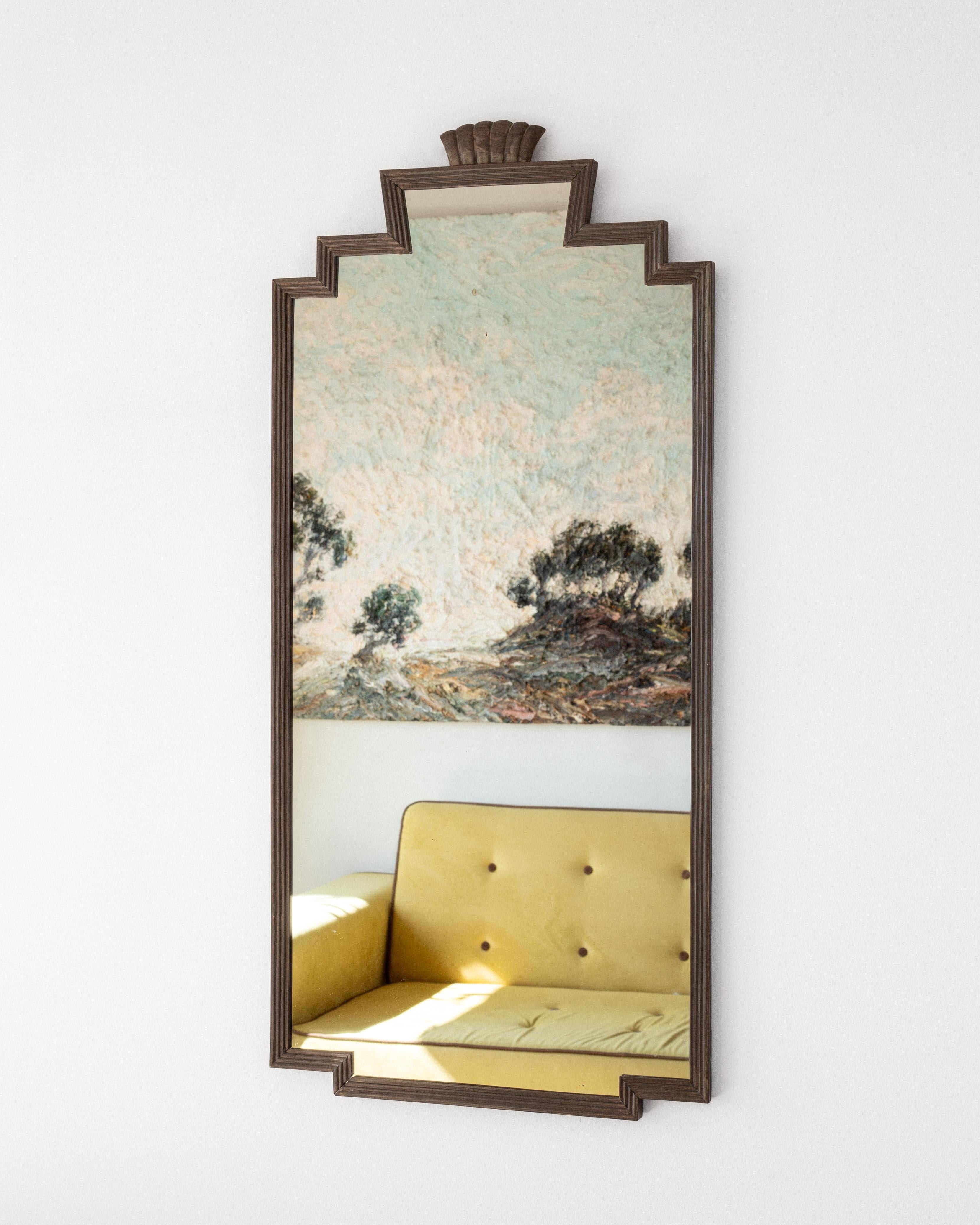 Bellissimo esempio di design scandinavo Art Deco, questo elegante specchio in bronzo degli anni '30 presenta il caratteristico design della cornice a gradini dell'epoca. Il dettaglio che spicca è l'ornamento a corona di conchiglie nella parte