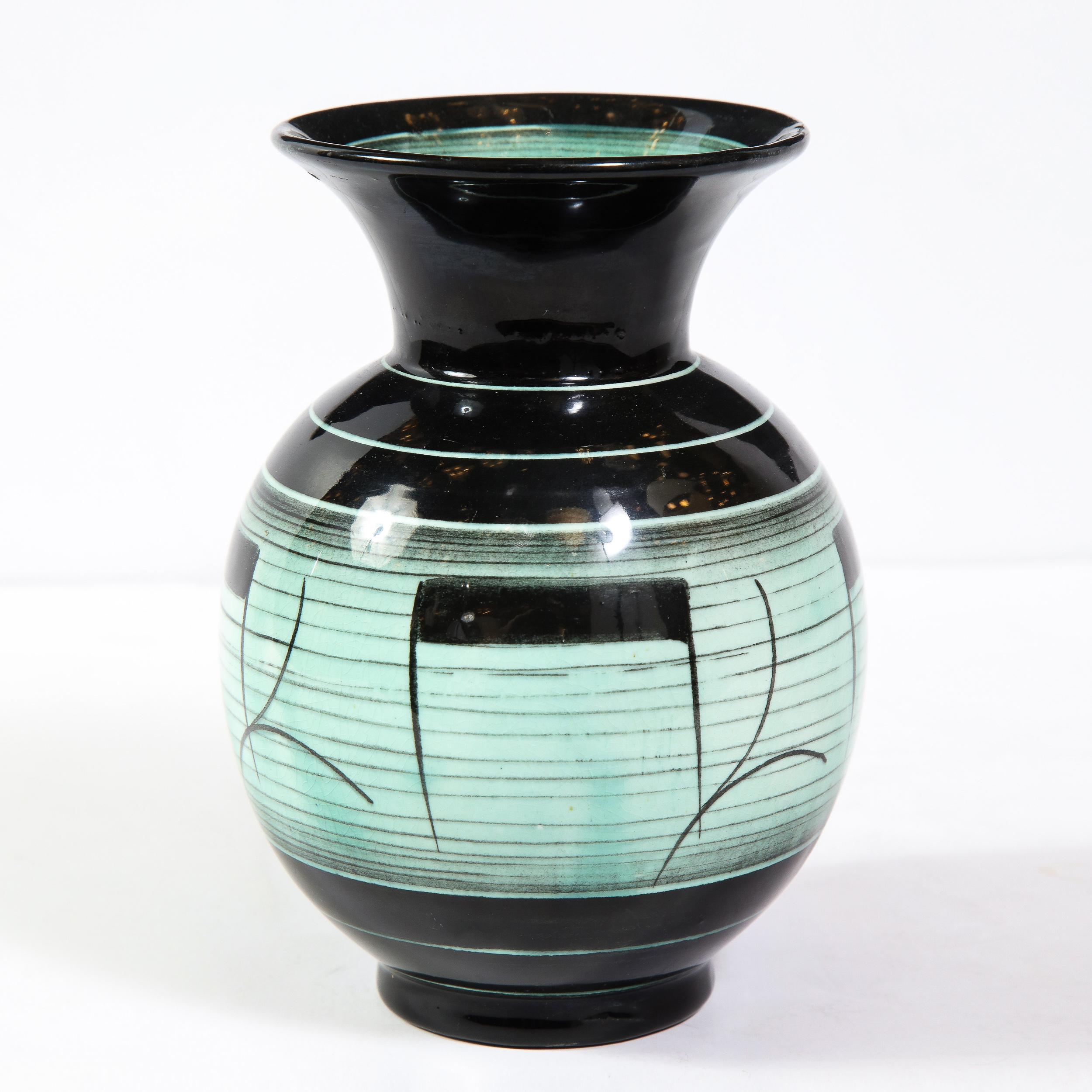 This elegant Art Deco glazed ceramic vase was designed by Ilse Claesson for Rörstrand in Sweden circa 1930. It features a stylized hour glass form with a striated onyx glazed base and a sea foam center with abstract hand painted motifs, as well as