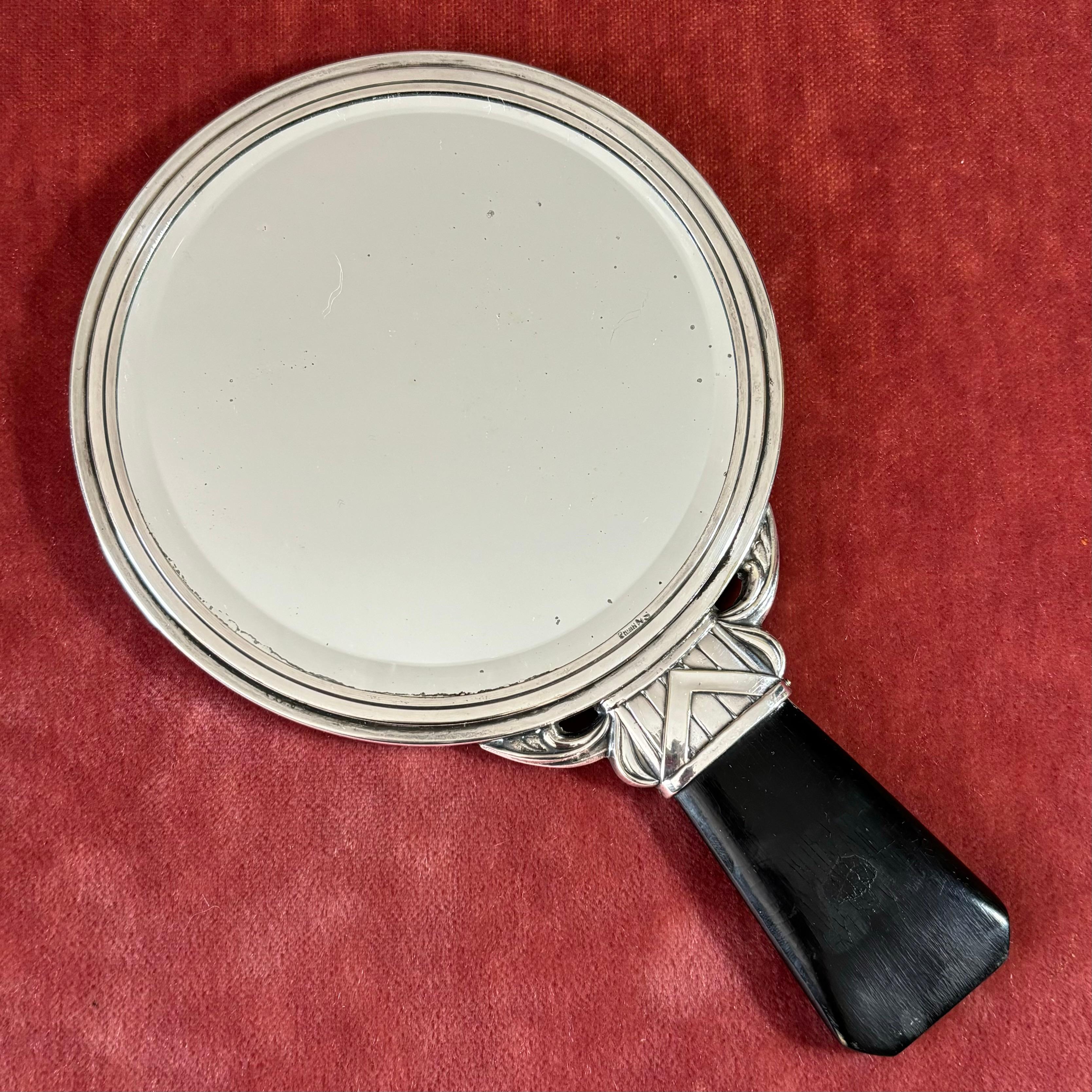 Gracieux miroir de courtoisie Art déco en maillechort, doté d'une poignée en bois noir. Il présente une ornementation classique et un verre miroir circulaire. Produit par un fabricant suédois non identifié dans les années 1930.