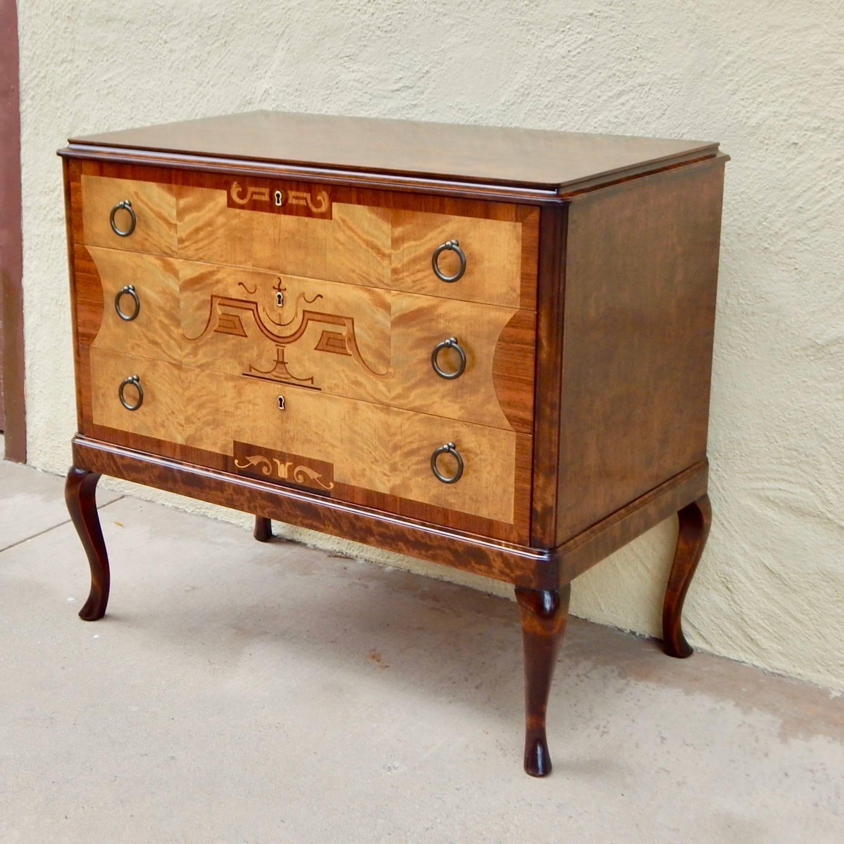 Swedish art deco chest of drawers with neo-classical inlaid frieze. Front rendered in highly figured golden flame birch wood. Inlay in rosewood, pear and ebony. 
All original pulls. This chest has just been beautifully restored by our craftsmen.