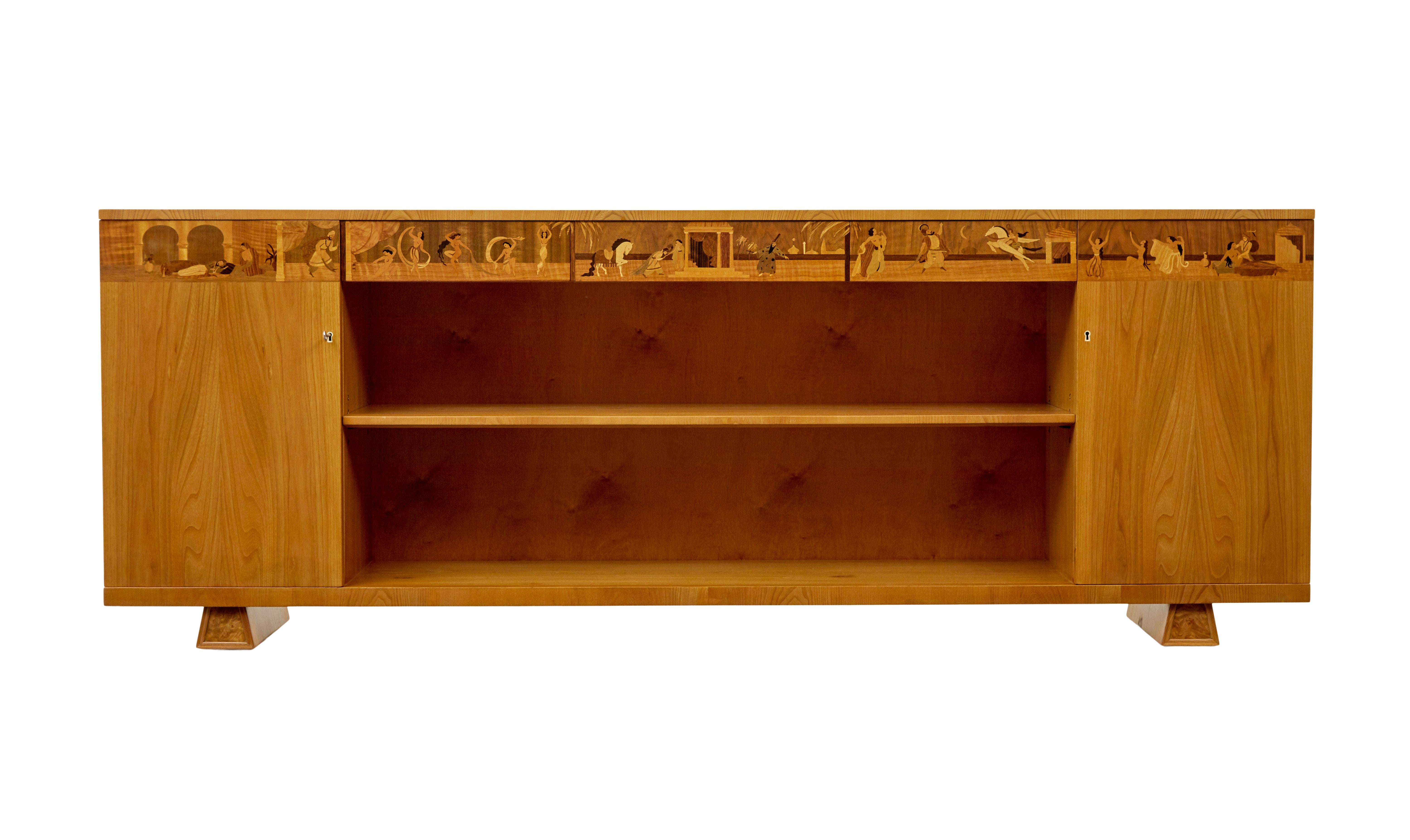Swedish art deco inlaid elm low bookcase by Mjölby Intarsia circa 1930.

Fine quality low open bookcase by Mjölby intarsia of Sweden showing the eastern fairytale of one thousand and one nights across the drawer fronts.

This long bookcase has been