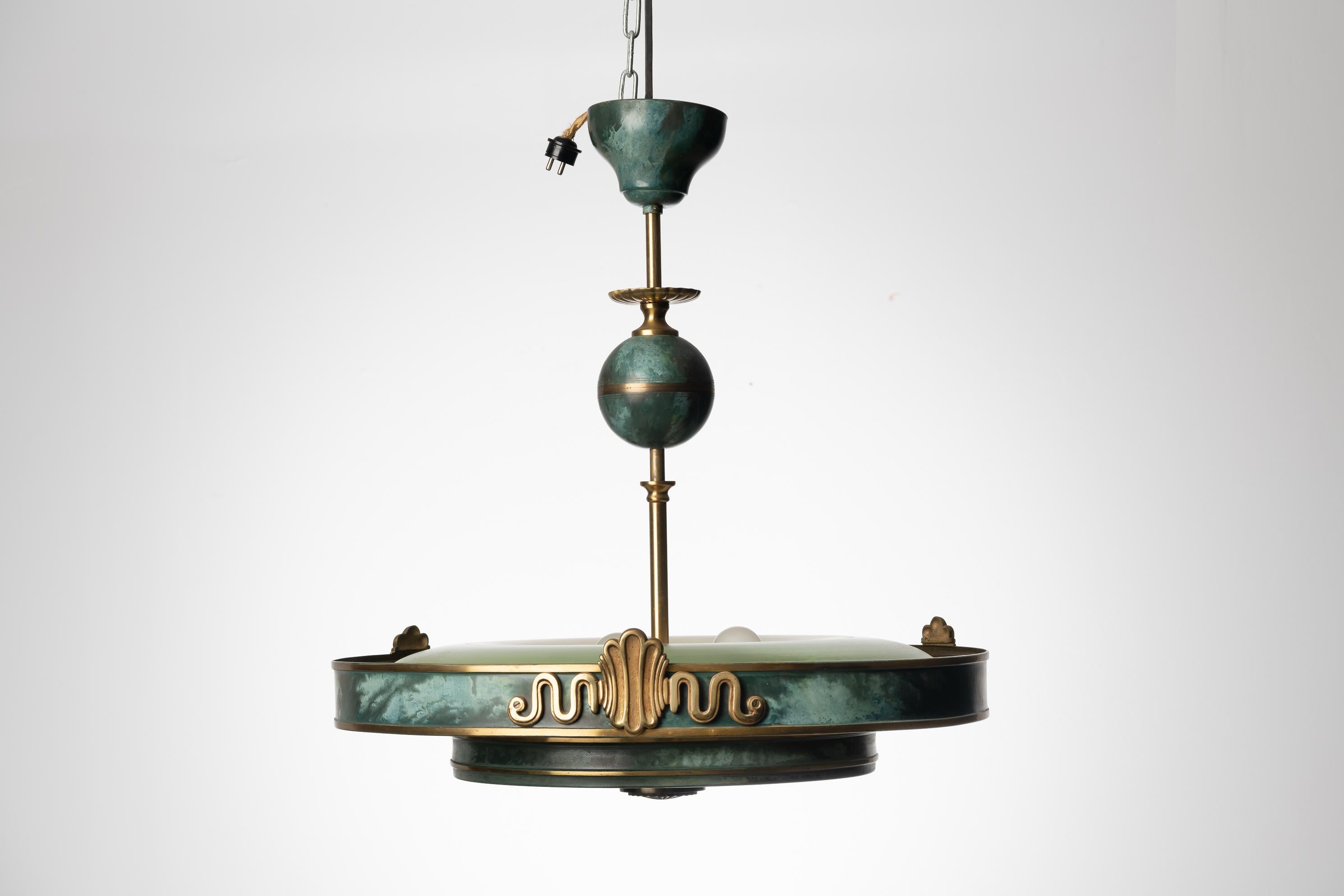 Art Deco ceiling light by Swedish manufacturer Böhlmarks Lampvarufabrik. The light is from around the 1930s. Made in plate metal that’s been patinated to become green with decorative elements in brass. The light is in the style of Harald Elof Notini