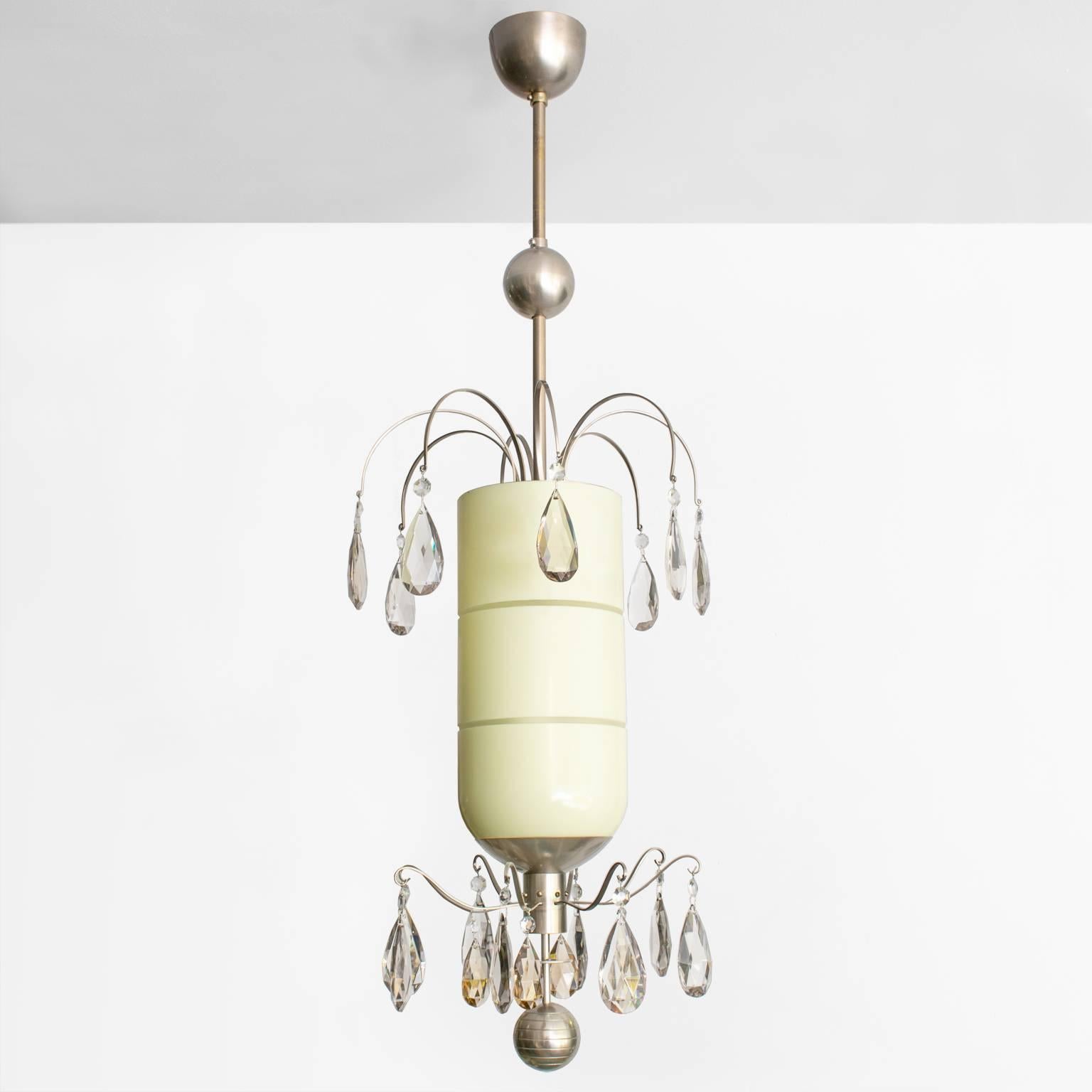 Swedish Art Deco pendant by Bohlmarks with two tiers of faceted crystal surrounding a capsule shaped modernist cased glass shade with horizontal etched grooves. The brass metal structure is plated with nickel from canopy to finial. Newly restored,