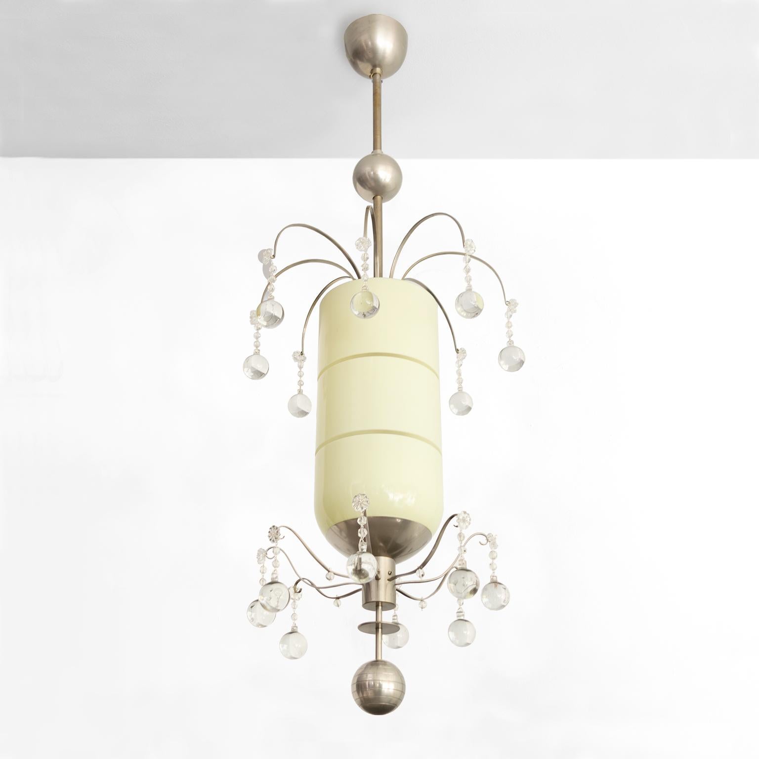 Swedish Art Deco pendant by Bohlmarks with 2 tiers of mixed size crystals surrounding a capsule shaped modernist cased glass shade with horizontal etched grooves. The brass metal structure is plated with nickel from canopy to finial. Newly restored,