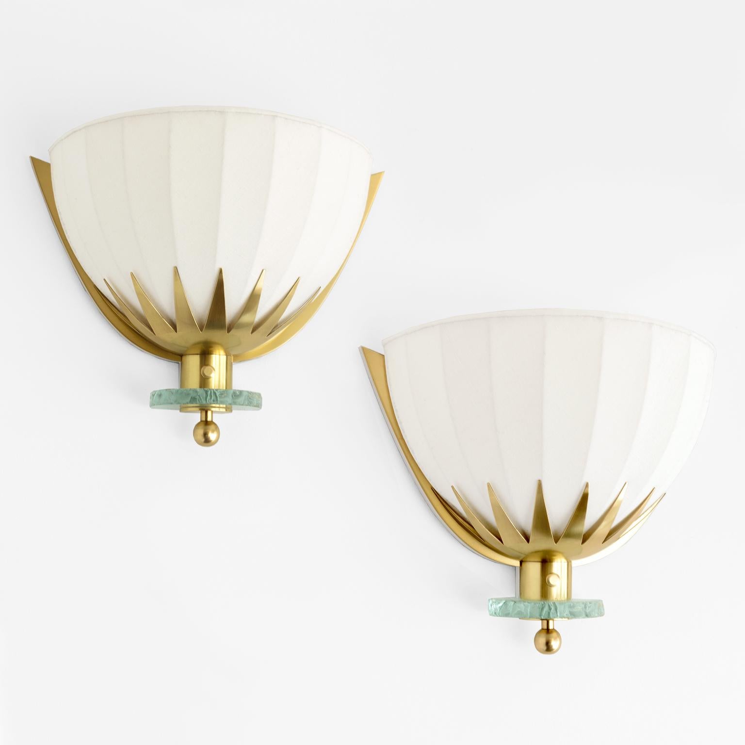 Swedish Art Deco demilune polished brass sconces with fanned fluted fabric covered shades. The brass frames have sunburst elements which hold the newly covered cotton-linen shades. The backplates are polished brass mounted on a painted wood frame, a