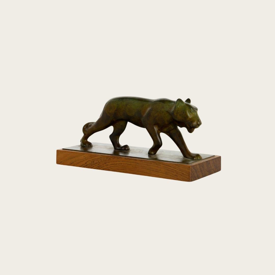 Années 1940, Suède. Sculpture Art Déco représentant un lion femelle en bronze patiné, montée sur une base en bois. L'artiste est anonyme.