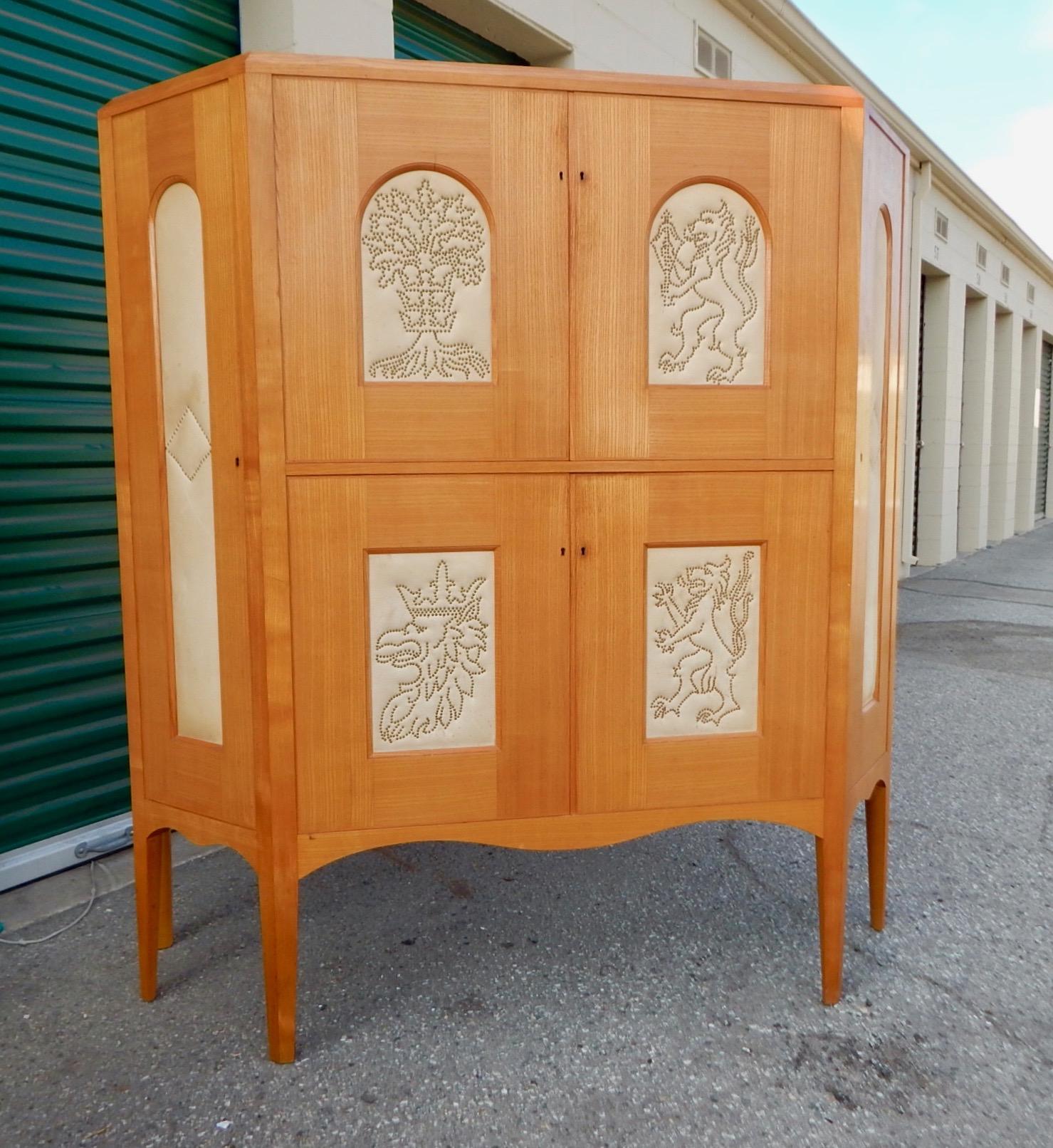 Art deco era storage cabinet by Otto Schulz for Boet it Gothenburg, Sweden circa 1930. Crafted in golden elm wood. The four nail head friezes on the doors are Schulz' trademark and represent the coats of arms of the Swedish states of Blekinge,