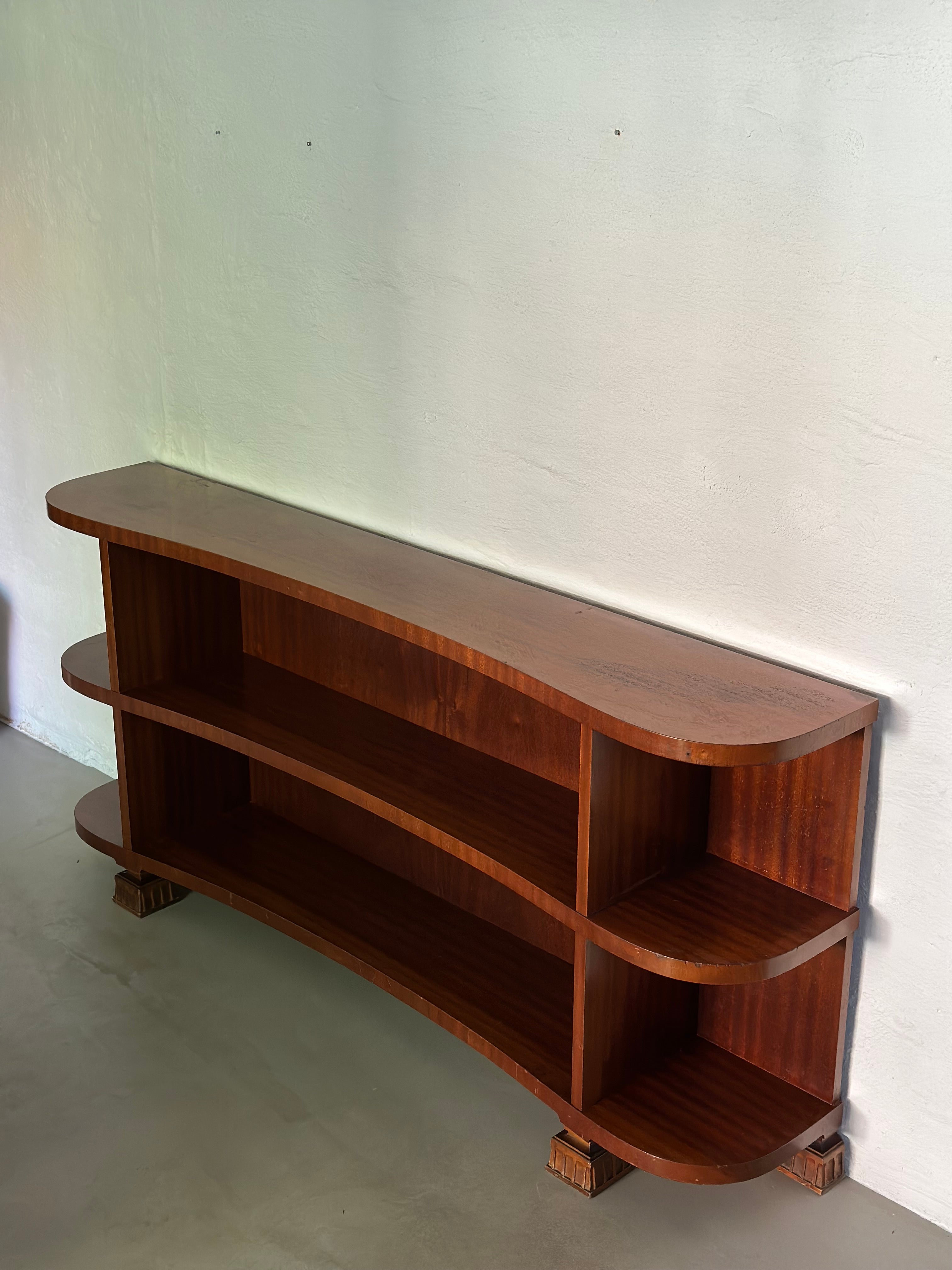Swedish Art Deco bookcase or shelf with a nicely curved front and Mahogany veneer. Very rare and decorative piece. By unknown maker, circa 1940s. 

Width: 165 cm
Depth: 30 cm
Height: 77 cm

In good vintage condition, light signs of wear. Some