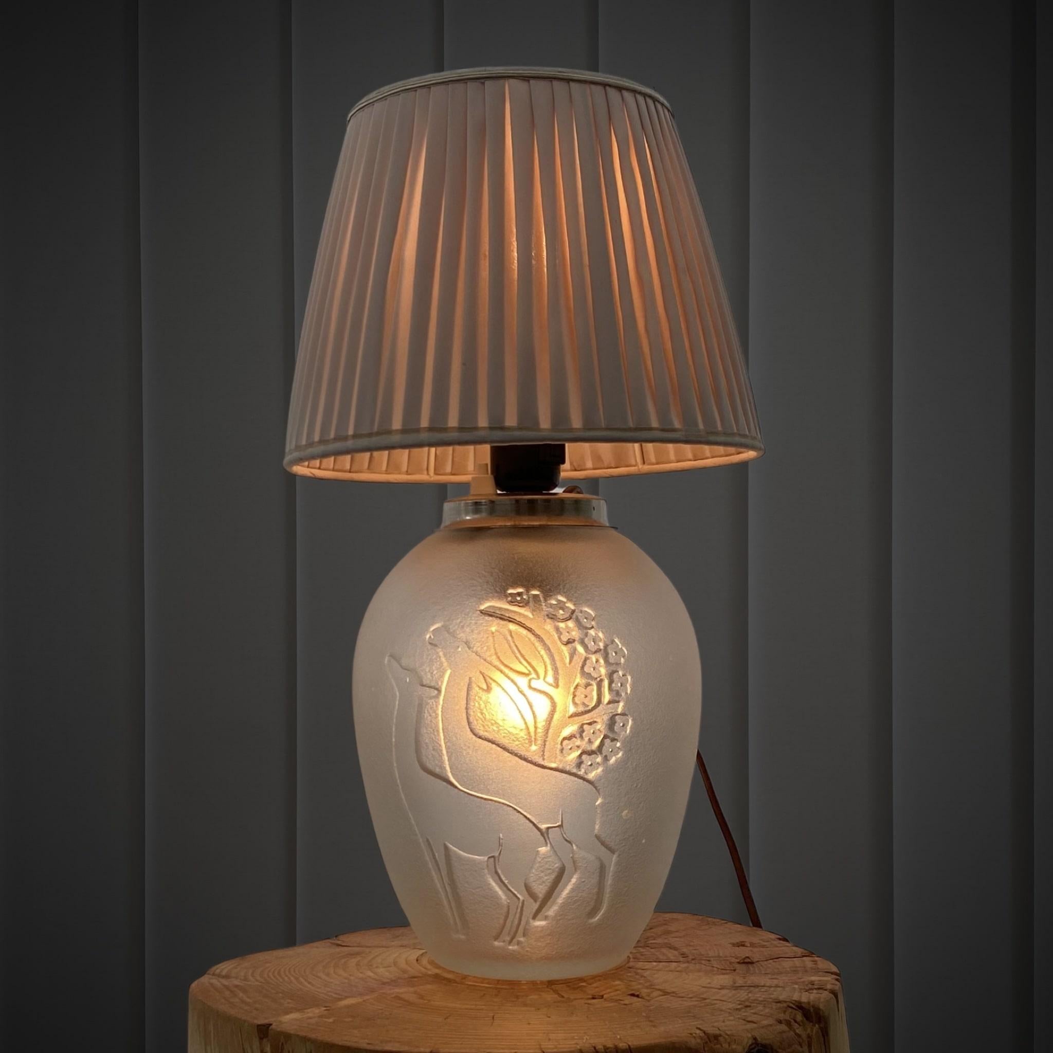 A graceful Swedish art deco table lamp, attributed to the artist Sven-Erik Skawonius, for the glassworks Kosta. No signature. The foot is made from blasted glass with two deer in strong relief. One lamp bulb at the top and one inside the foot.