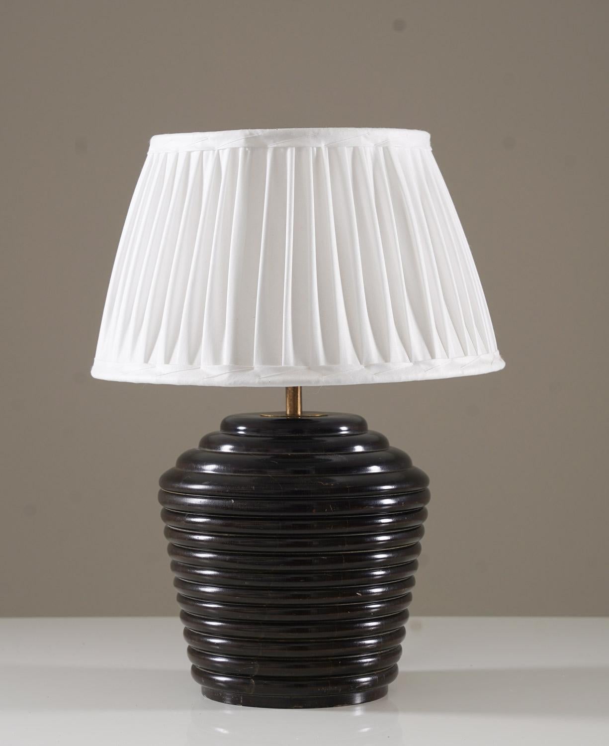 Une exquise lampe de table Art déco des années 1930, fabriquée en Suède, dont l'esthétique est à la fois audacieuse et raffinée. La base de la lampe est fabriquée en bois nervuré richement teinté, créant une forme sculpturale et texturée qui incarne