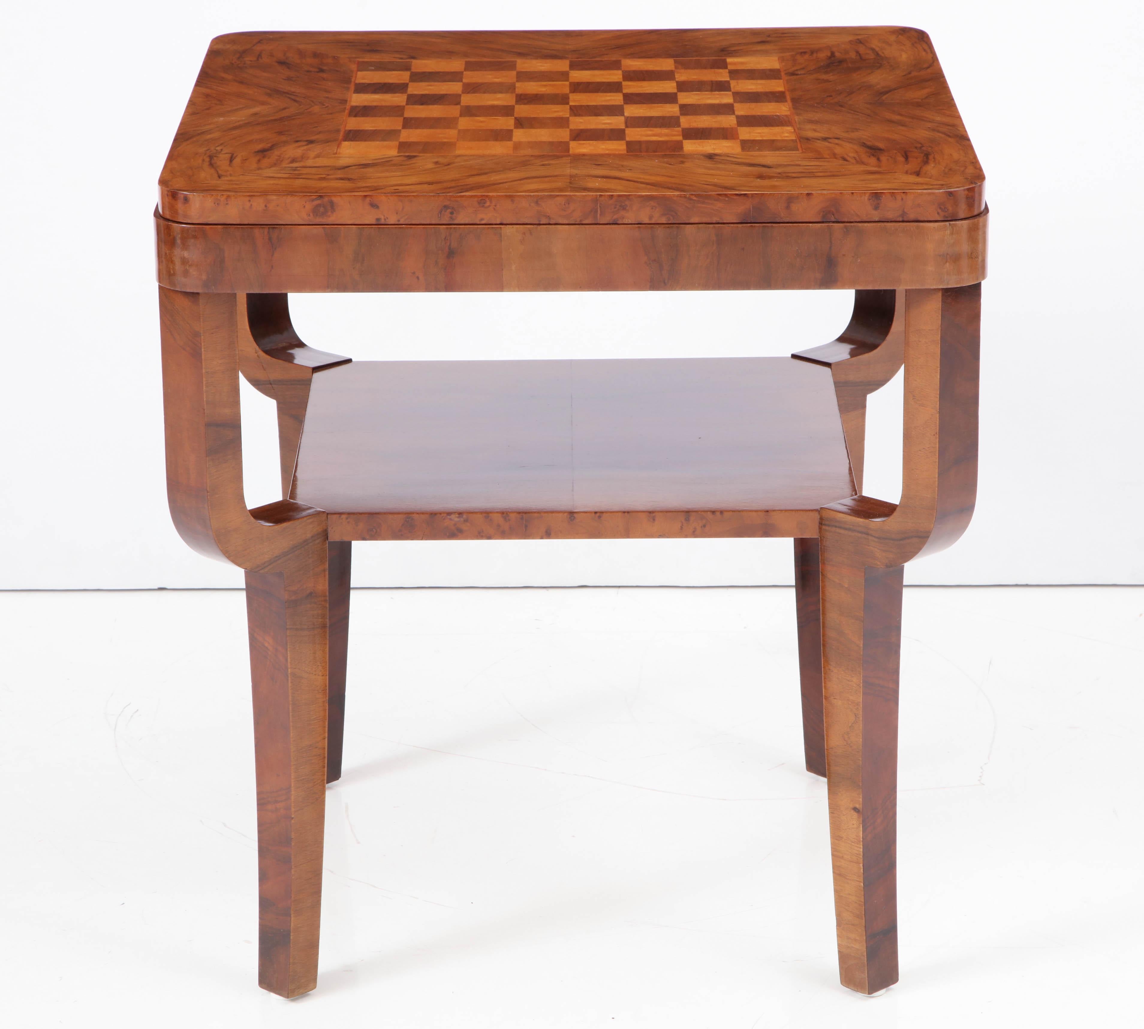 A Swedish Art Deco walnut and birchwood games table, circa 1930s, the slightly stepped square top with an inset games board, raised on curved and square legs with a shelf.