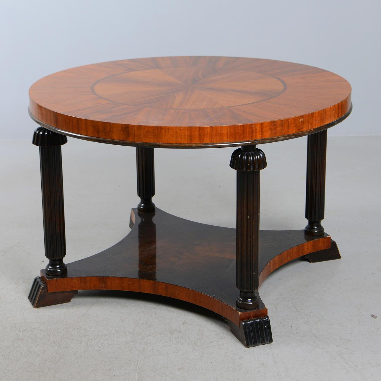 Elegante mesa redonda sueca Art Déco fabricada por Reimers Mjölby en la década de 1920. La mesa presenta un llamativo tablero chapado en nogal y caoba con decoración geométrica de intarsia finamente ejecutada. Apoyado en cuatro patas acanaladas,