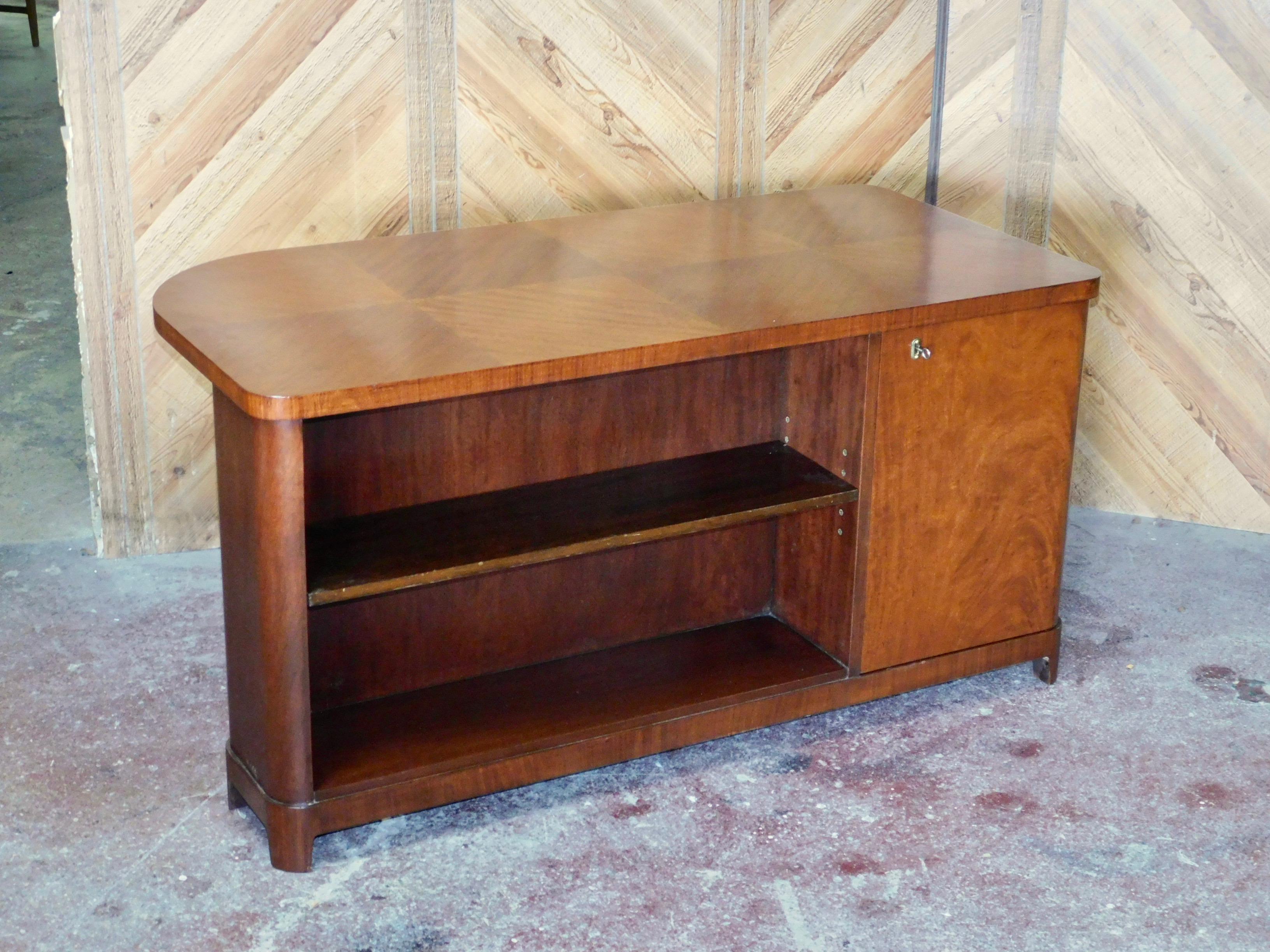 Swedish art moderne desk rendered in bookmatched flame mahogany. With built in book case at back. With multiple interior drawers. With original key. In impeccable restored condition with original key.