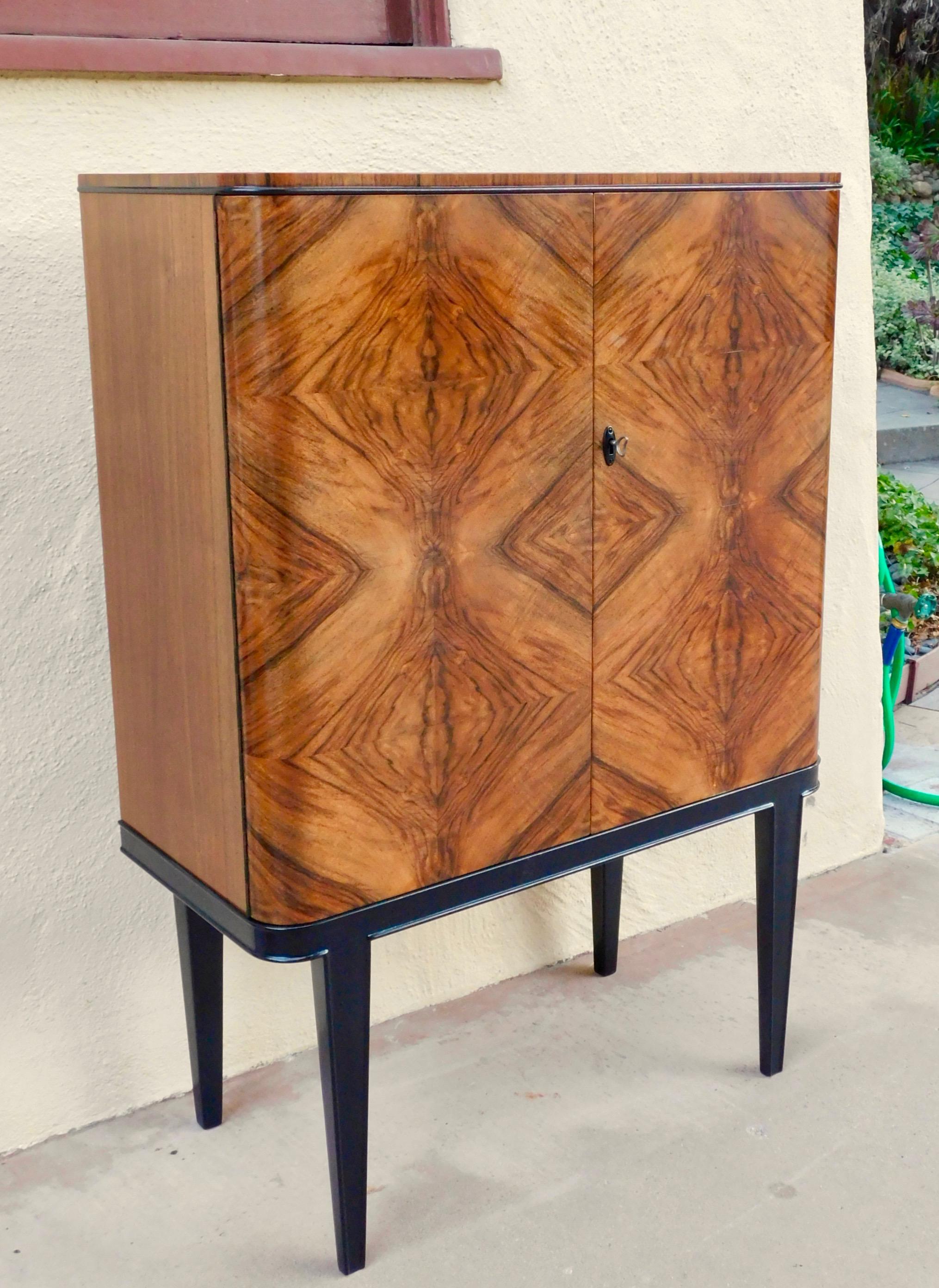 Swedish art moderne dry bar or sideboard in bookmatched, highly figured walnut.
Made at Lingstroms in Sweden, circa 1940. Interior is composed of drawers and adjustable/removable shelves-you can see the shelves (they are not pictured assembled) in