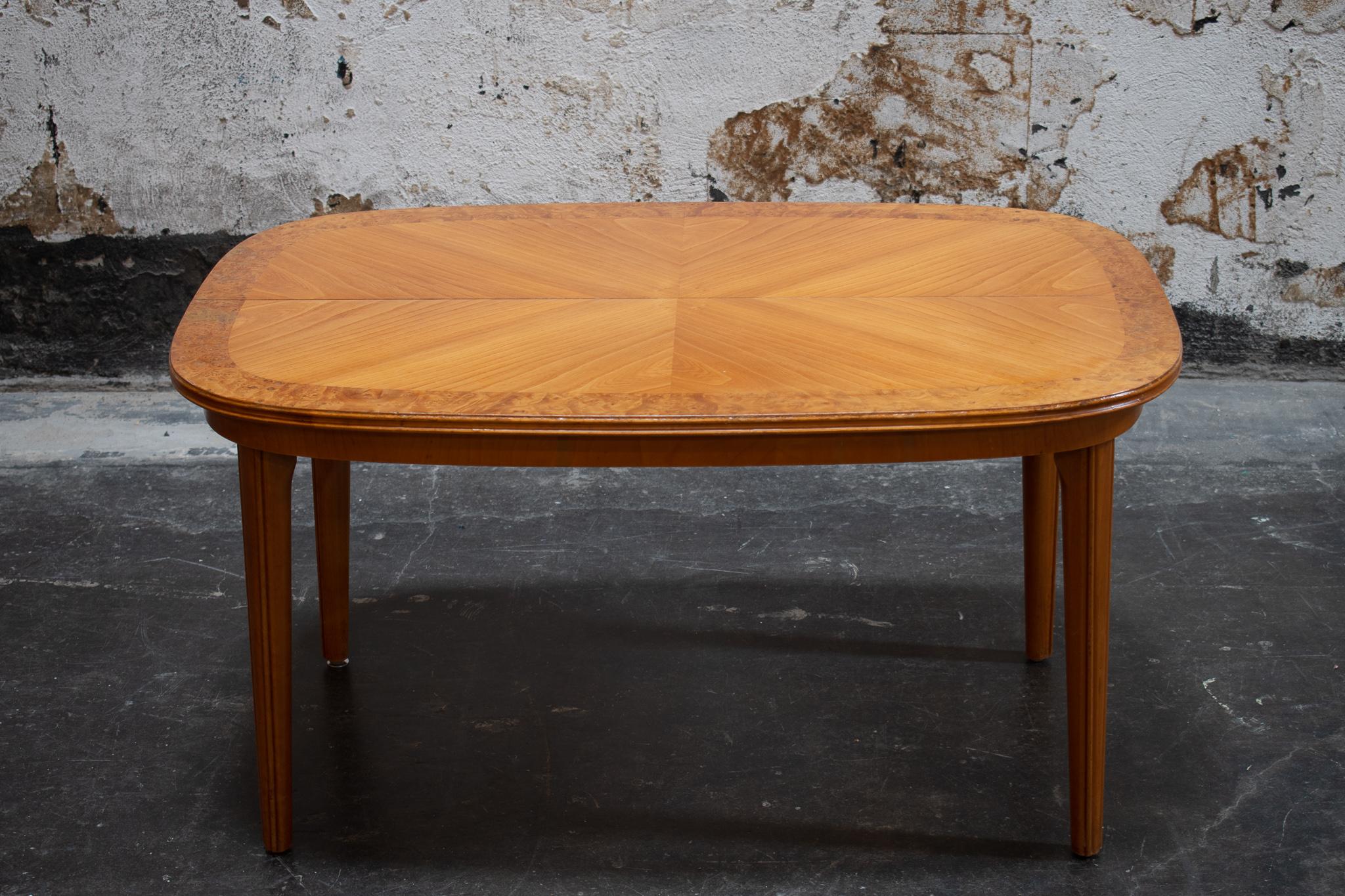 Gorgeous Art Deco coffee table made in Sweden. Features burl veneer border, reeded legs, and matchbooked Golden Elm veneer top. This table used to be adjustable, now the two sides are permanently affixed to each other, leaving a seam running