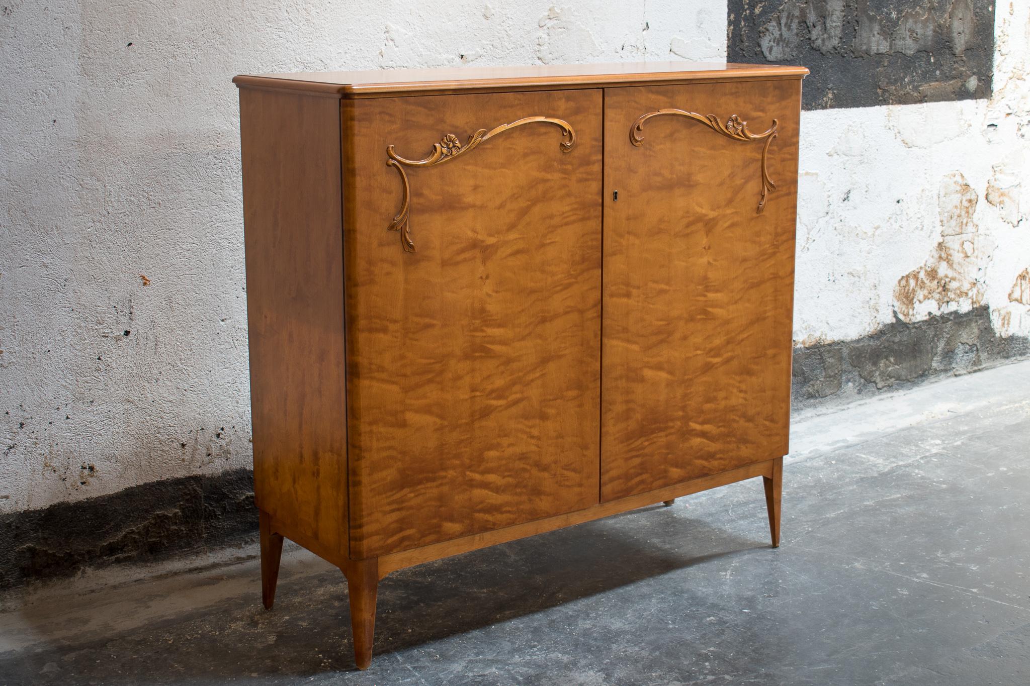 Art Moderne Credenza cabinet made of Golden Flame Birch in Sweden, circa 1940. Two-door storage cabinet has beautiful relief carved floral details on the doors. The wood has what is known as a flame grain pattern that has mellowed to a rich amber