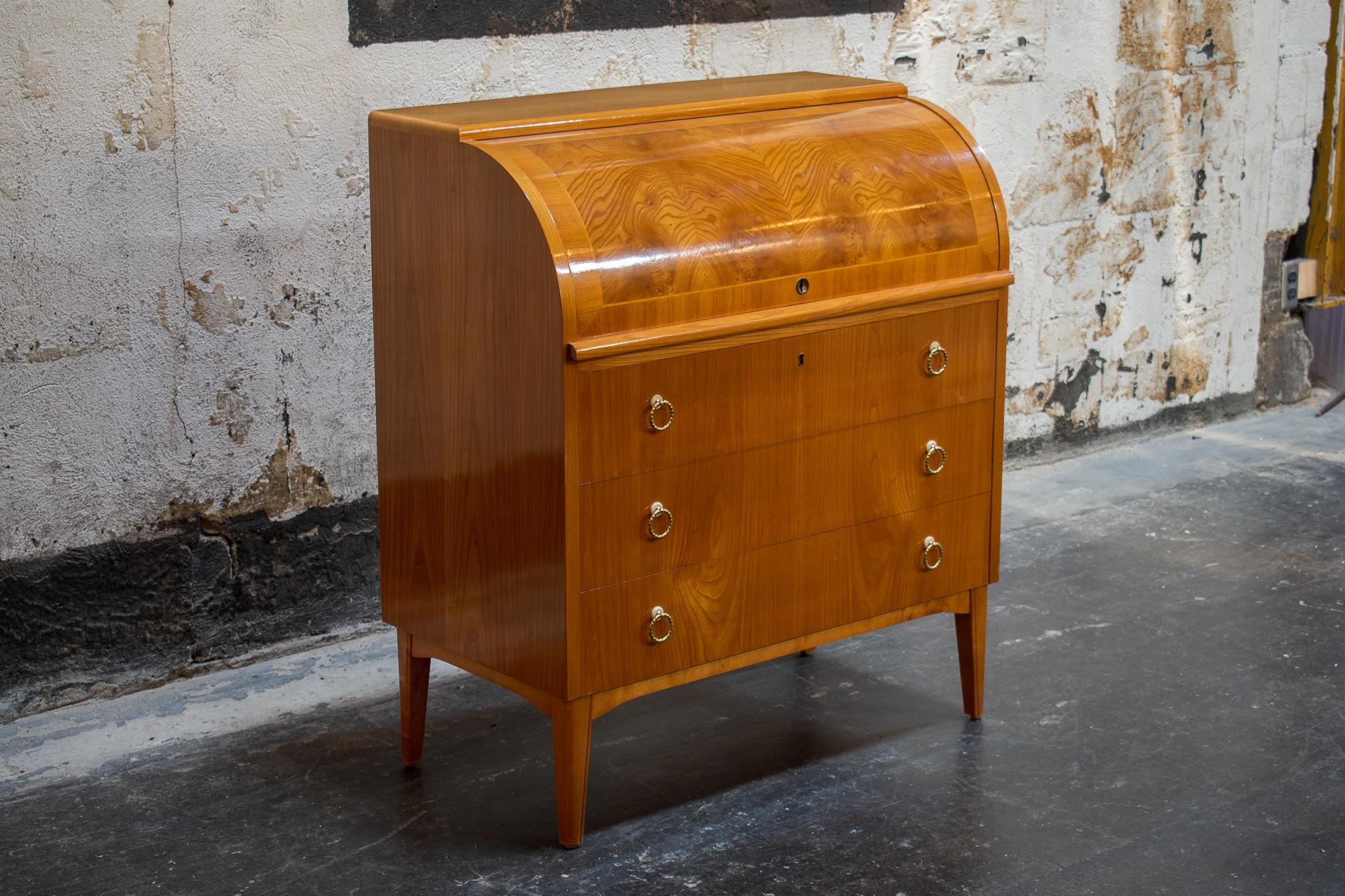 Beautiful roll-top writing desk in Elm with Bookmatched Elm veneer. Top rolls up to reveal cubbyholes with burl elm accents, drawers, and a retractable desktop. Lower section includes three large drawers for excellent storage. This stunning piece