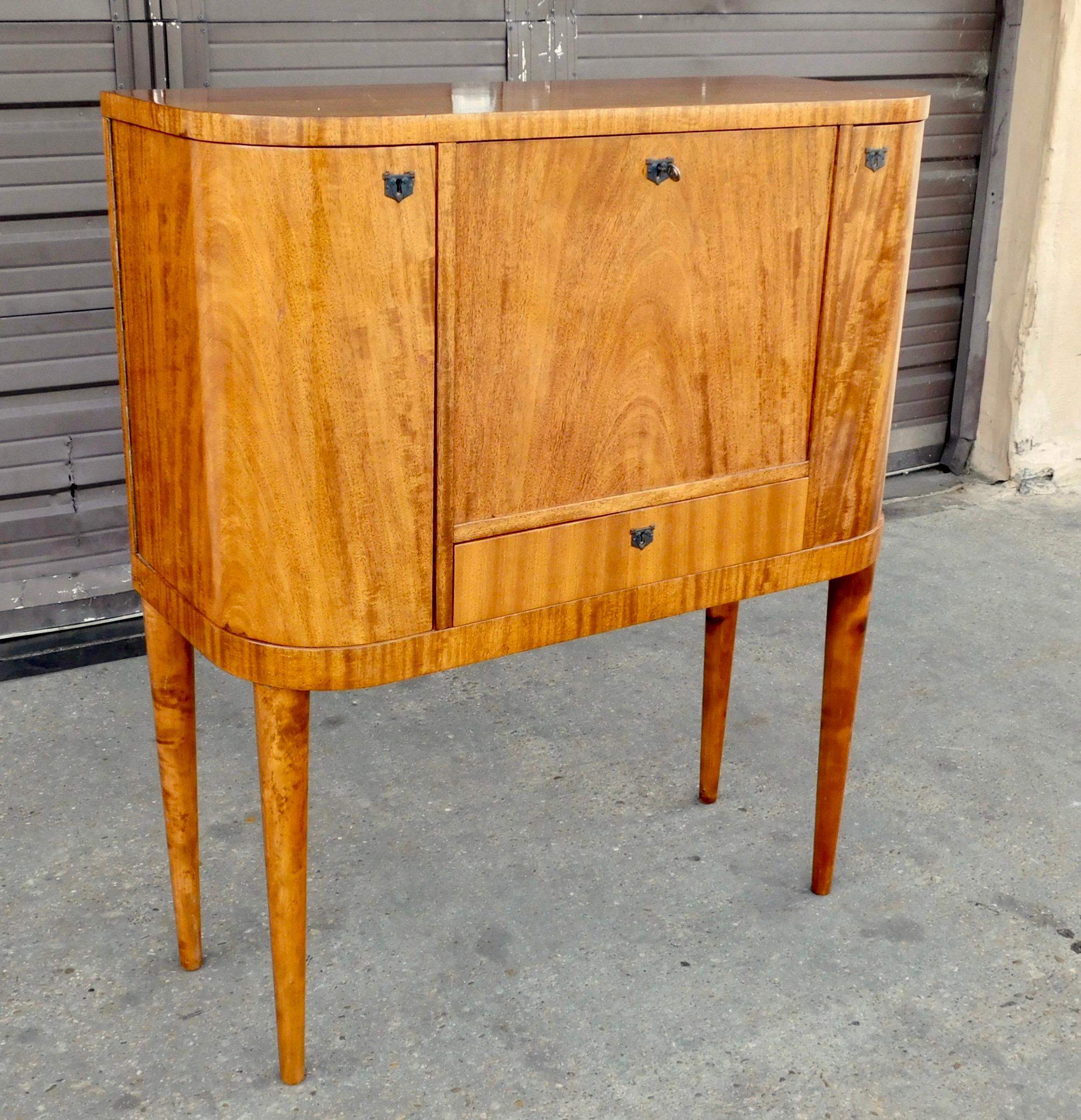 Swedish Art Moderne drop front secretary desk with side cabinets for bottle storage.
Rendered in open grain, natural color Honduran mahogany.
With interior drawers and desk flap which is stabile and great for supporting (and storing) a lap top