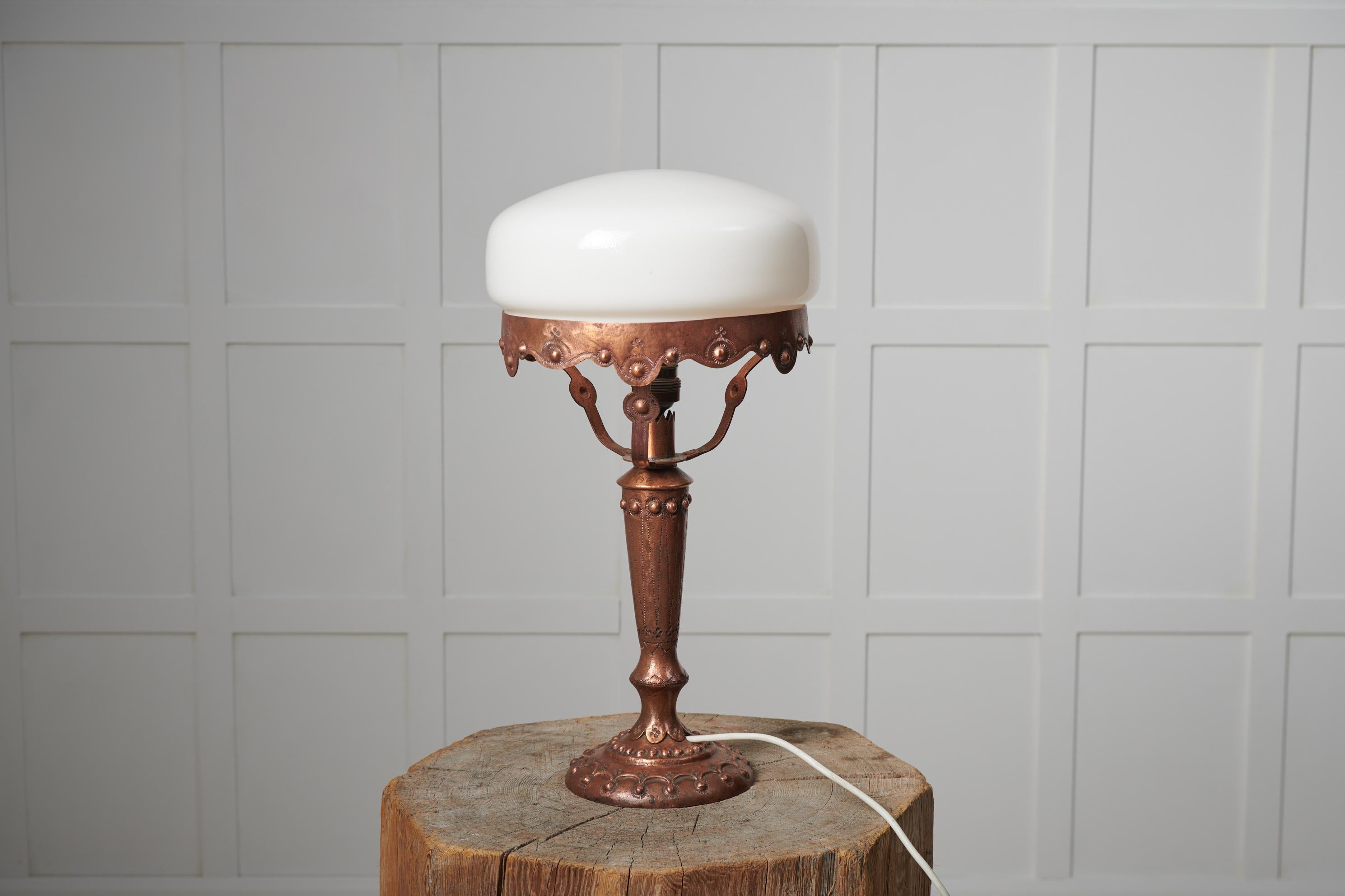 Lampe suédoise art nouveau des années 1920. La lampe de table a une base fabriquée à la main en laiton massif avec décor. L'abat-jour est rond et réalisé en verre opalin blanc. Le luminaire est en bon état vintage avec quelques traces mineures
