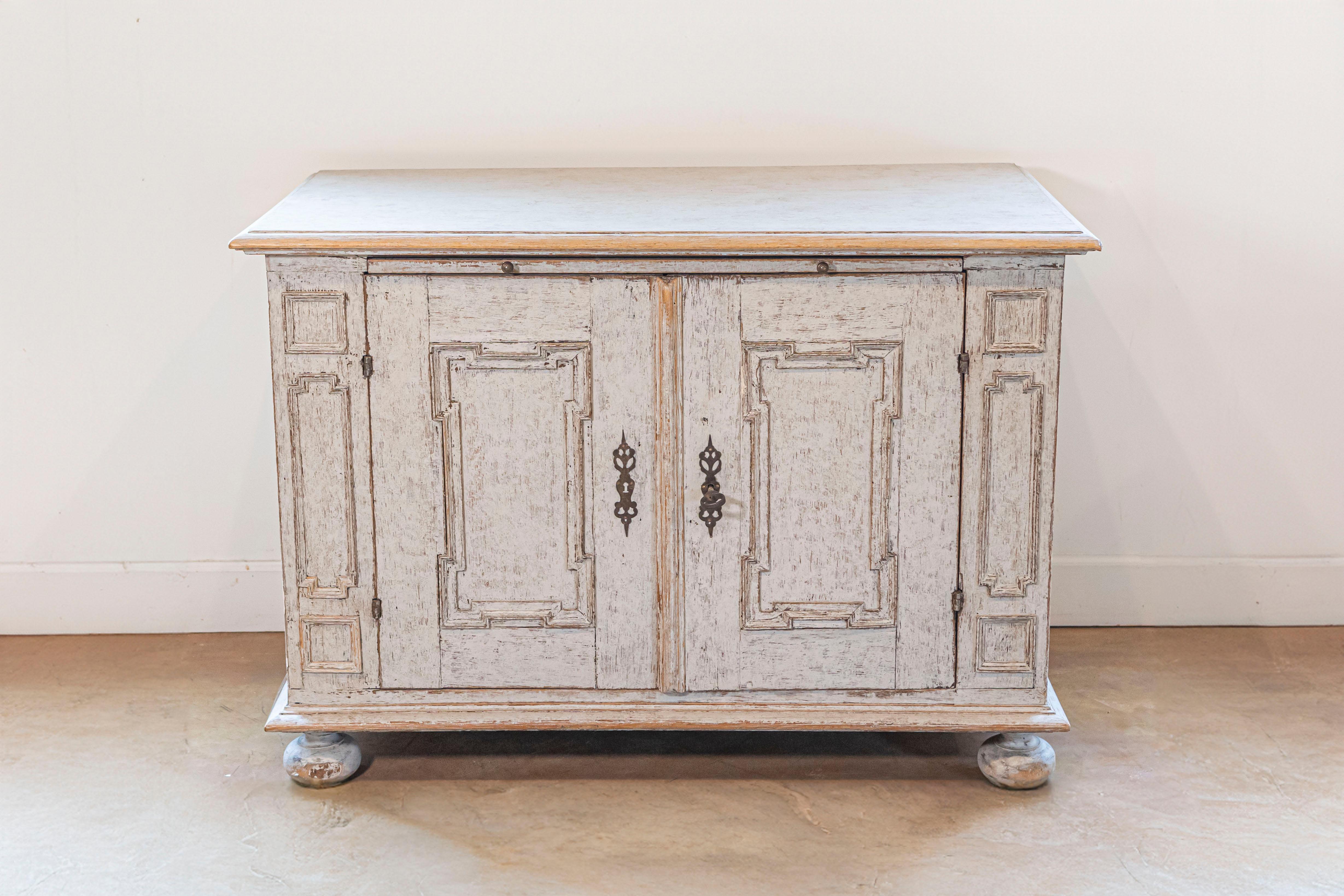 Ein schwedisches Buffet aus bemaltem Barockholz aus der Mitte des 18. Jahrhunderts, mit zwei Türen, geometrisch geschnitzten Paneelen, ausziehbaren Füßen und schöner Patina. Dieses bemalte Buffet, das im zweiten Viertel des 18. Jahrhunderts in