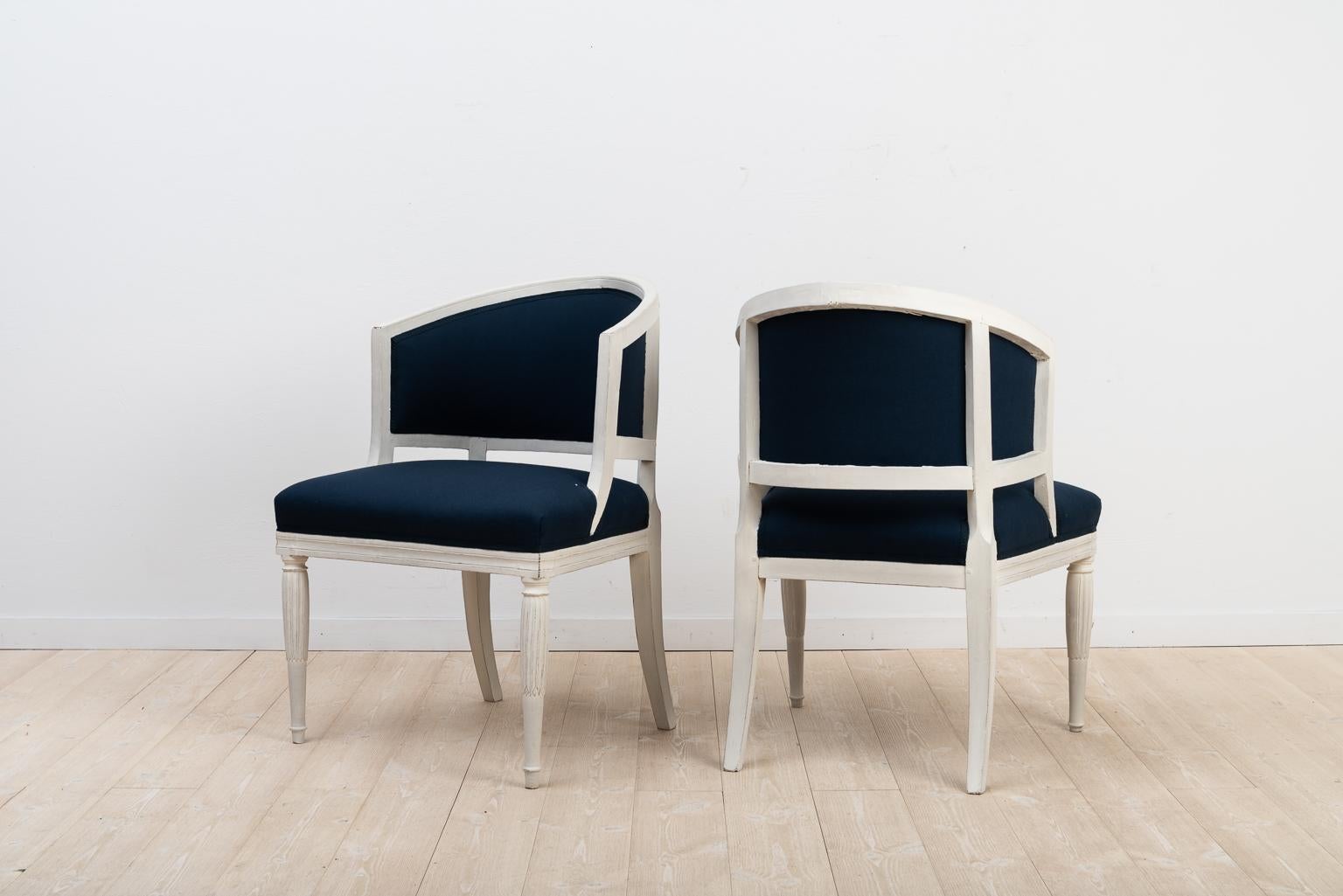 Swedish gustavian barrel back chairs in a set of two. The chairs are a true pair and manufactured during the early 1800s, around 1820. The chairs have been newly renovated with new padding and upholstery in a rich dark blue fabric that contrasts