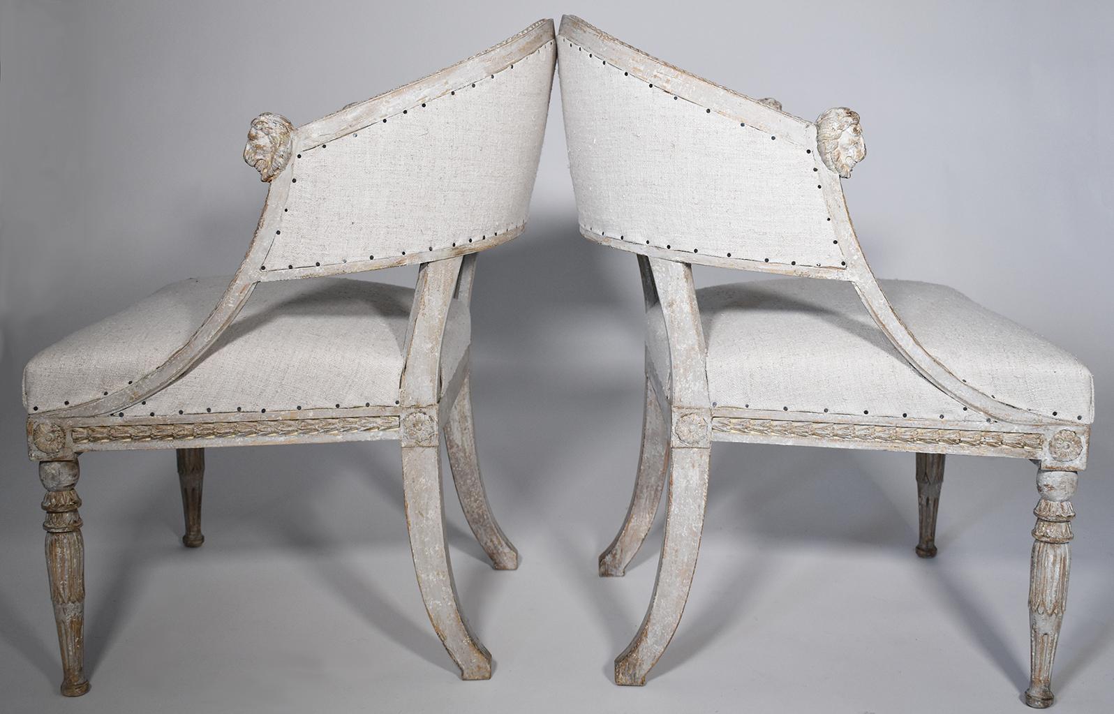Elegant pair of 19th century Gustavian barrel back armchairs with detailed lions' head carvings on arms, saber legs, scraped to original patina with European Burlap. Carving on the chair back at top of seat rest, sides, apron and legs add to the