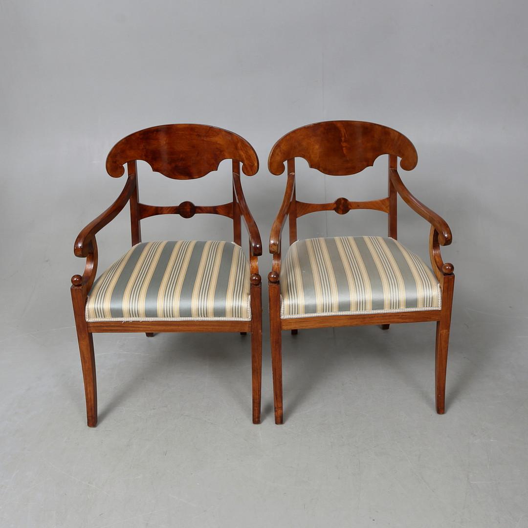 Swedish Biedermeier Empire pair of carver chairs in highly quilted golden birch veneers finished in the Classic mid oak color French polish finish with roundel motif on the arms and classic 'napoleon hat' seat back.

They have fully webbed seats