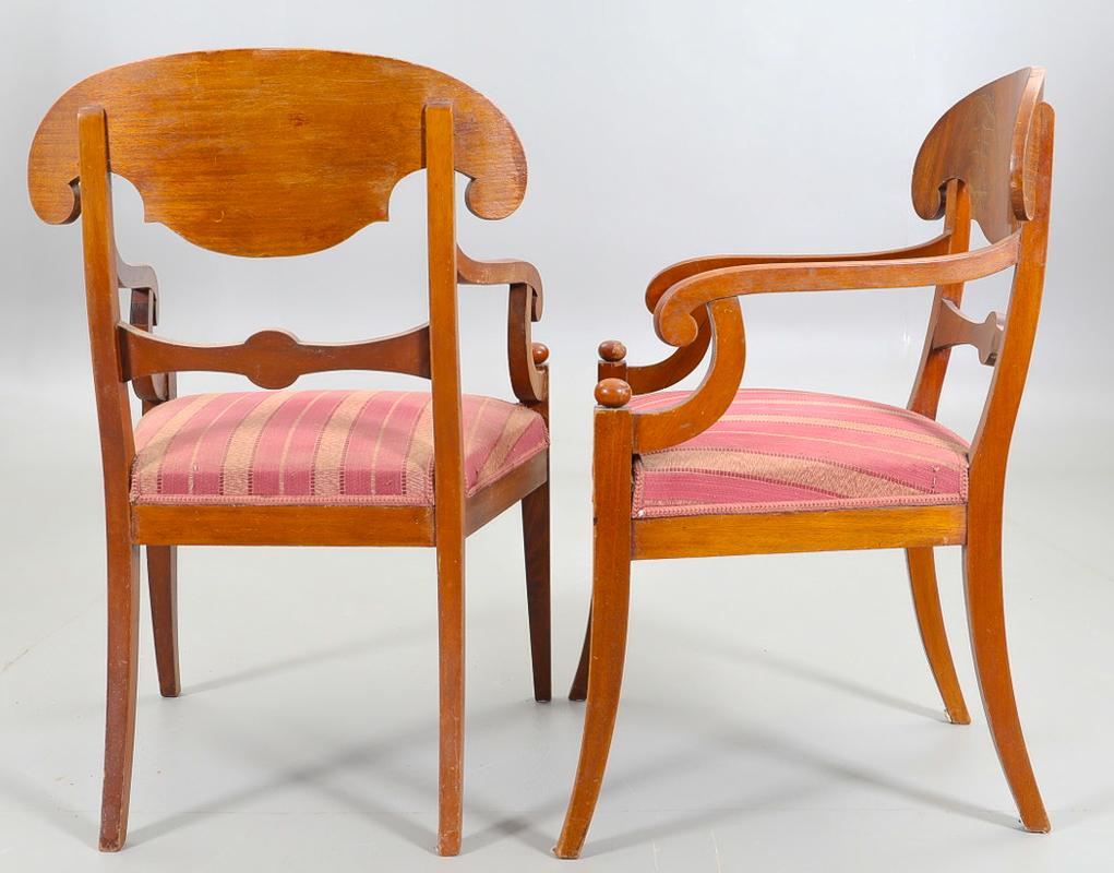 Swedish Biedermeier Empire pair of carver chairs in highly quilted golden birch veneers finished in the Classic honey color French polish finish with ormolu roundel on the arms and fan motifs in the seat back.

They have fully webbed seats for
