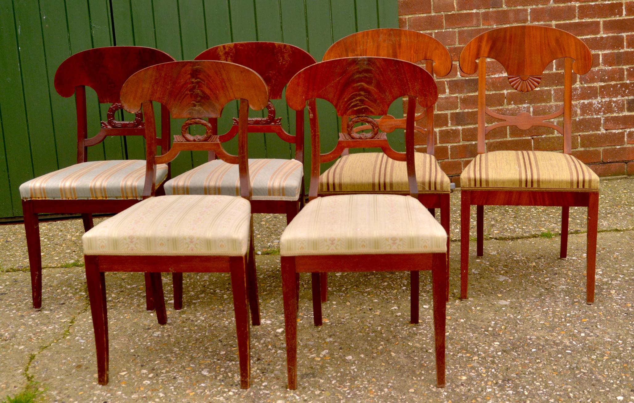 Unusual mixed set of antique Swedish flame mahogany Biedermeier dining chairs with the distinctive curved seat back, wreath and fan motifs and gracefully curved front legs.

The top grade flame veneers are brought to life in a rich darker french