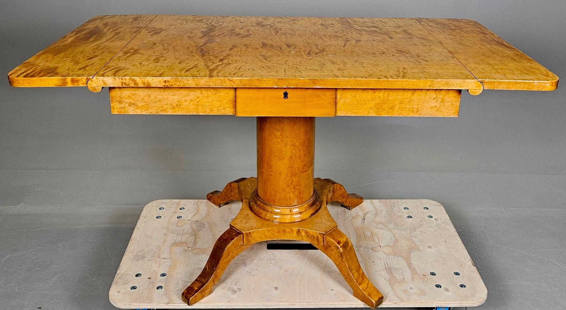 Antico tavolo svedese Biedermeier con impiallacciatura di betulla dorata a righe tigrate e quattro eleganti piedi curvi.

La colonna del piedistallo, in particolare, presenta delle bellissime volute nel legno e anche sui piedi.

Le ali del tavolo