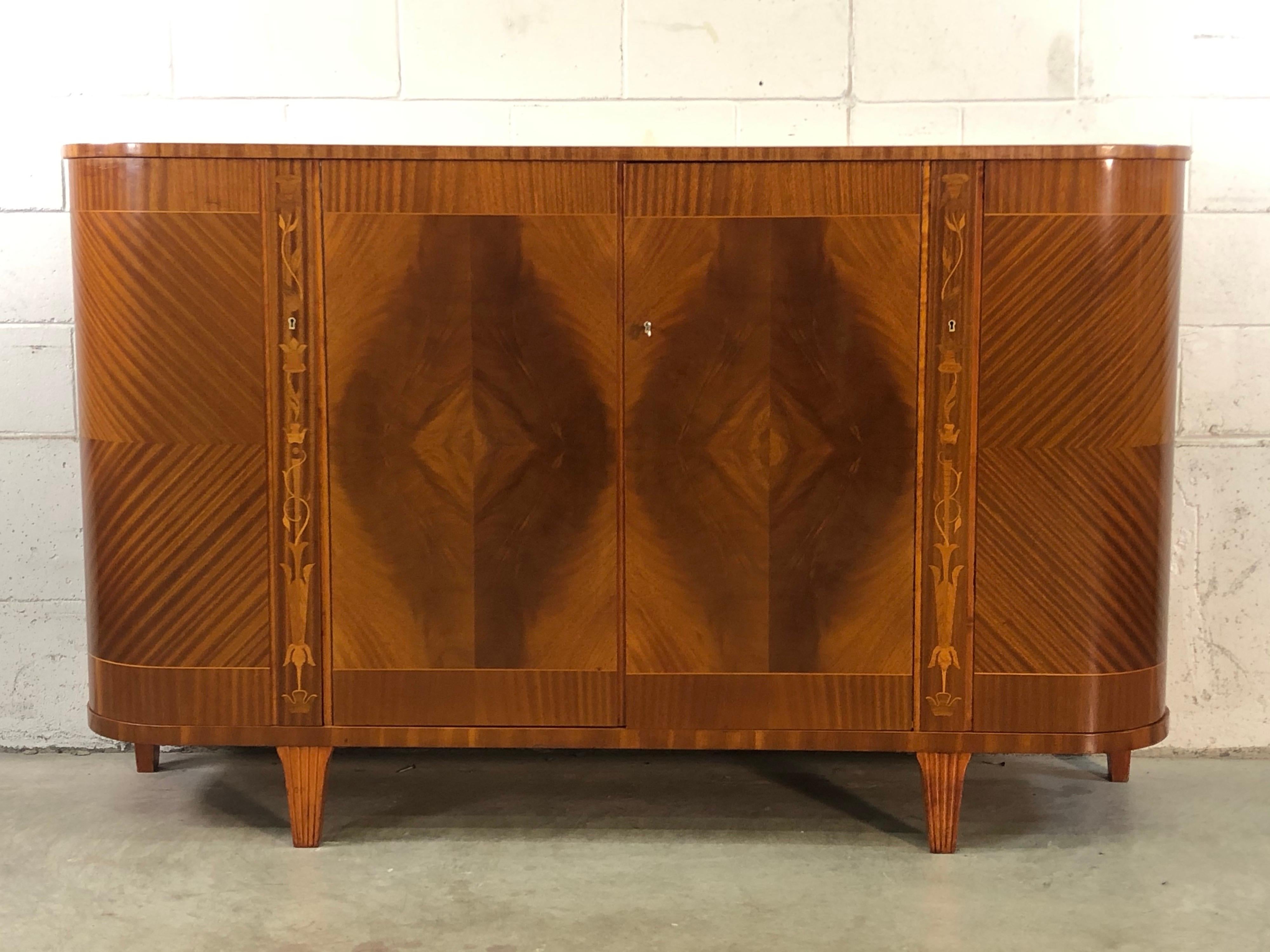 Swedish Biedermeier tiger maple demilune buffet server with floral inlay accents and beautifully curved sides. Front of the server has a matchbook veneer. Shelves, drawers and open storage hold a vast amount of goods. No marks.