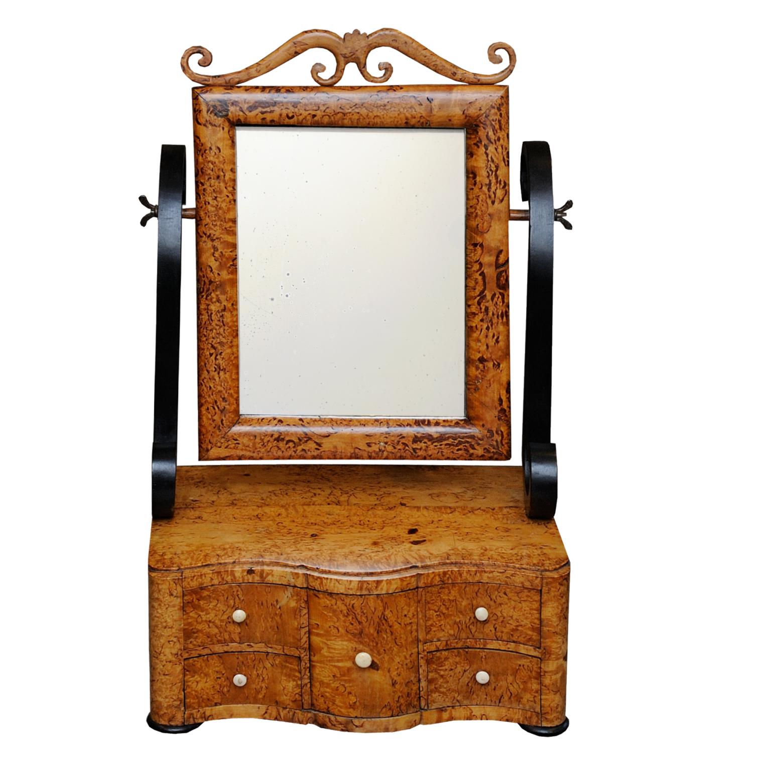 This is a rather beautiful Swedish Biedermeier toilet mirror, made in beautifully figured Karelian birch, with ebonized scrolling supports and original lightly foxed mirror plate. Standing on a wavy fronted suite of drawers, circa 1820.