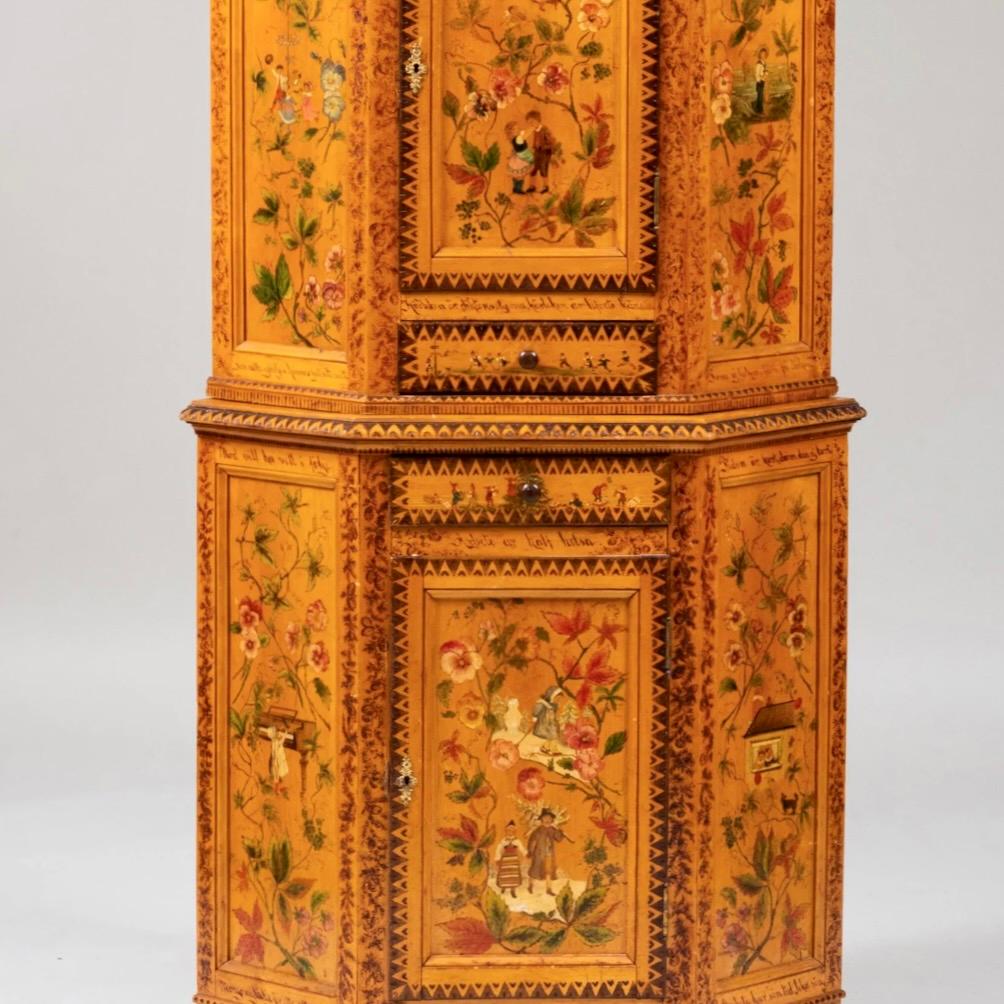 A charming and beautifully decorated petite light golden wood two piece corner cupboard with two cabinets and two drawers, working locks with a key. Decoration includes punchwork patterns enhanced with contrasting dark brown coloring along with