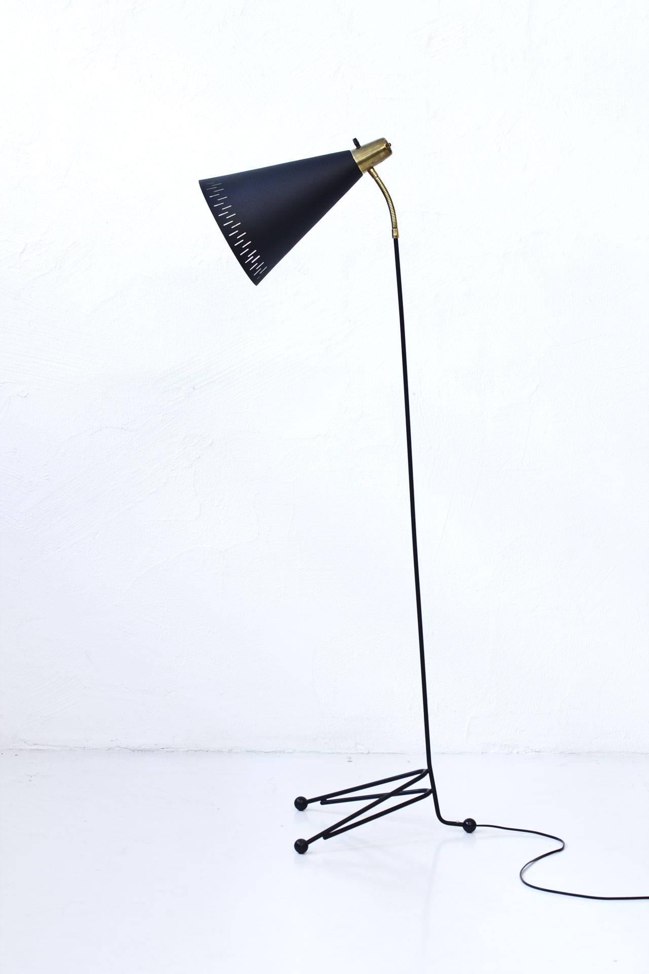 Swedish floor lamp, marked EAE produced during the 1950s. Metal stem, aluminum shade in black lacquer finish. Adjustable reflector with flexible arm in brass. Light switch on top in working condition.