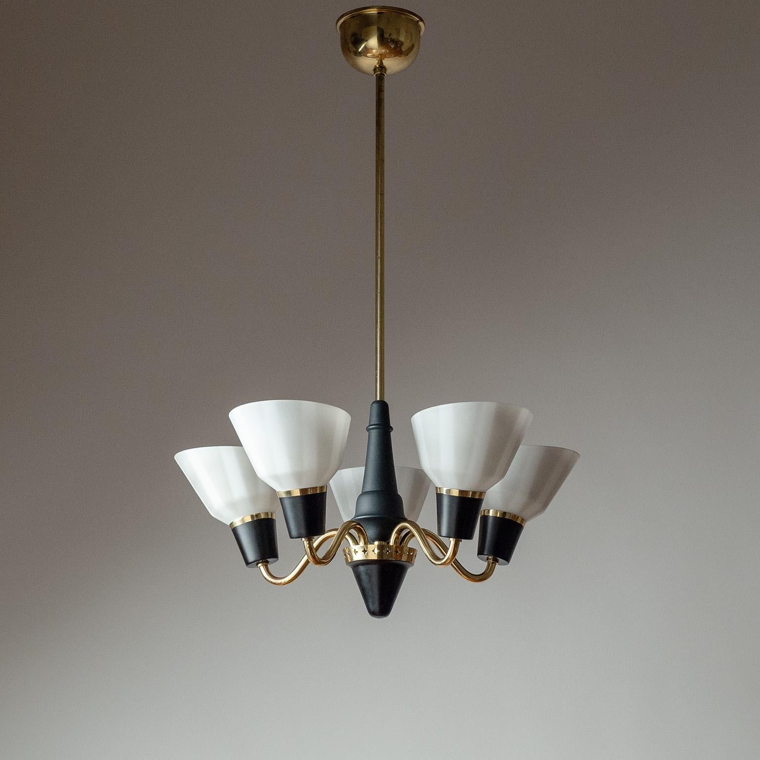 Fine Swedish brass chandelier from the 1950s with striped glass diffusers. The brass socket covers as well as the turned wood centerpiece are partially lacquered in black. Very nice original condition with a light patina on the brass. Five original