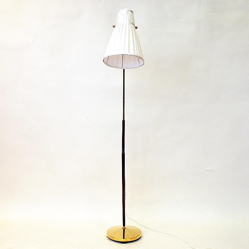 A gorgeous brass and teak floor lamp designed by Hans Bergström and made by ASEA in the 1950s Sweden. Beautiful patina and lovely design with a cone shaped original lampshade with white handsewn folded fabric. The lower part of the lamp is of teak