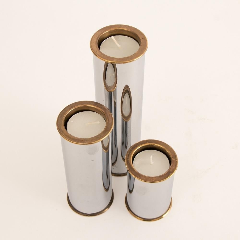 A set of three graduated brass and chrome modernist candleholders by Swedish designer Staffan Englesson, fully marked to base.

Measures: Large - H: 18.3cm, W: 5.5cm, D: 5.5cm

Medium - H: 13.5cm, W: 5.5cm, D: 5.5cm

Small - H: 8cm, W: 5.5cm,