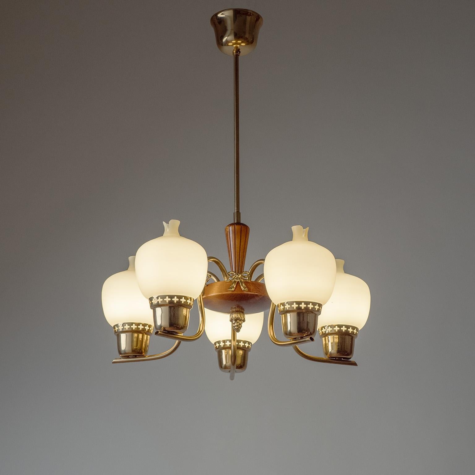 Encantadora araña sueca de latón, cristal y madera de los años 1940-1950. Estructura de latón pulido alrededor de un centro de madera con adornos de latón fundido. Los difusores de cristal de forma única tienen una capa exterior tintada de ámbar con